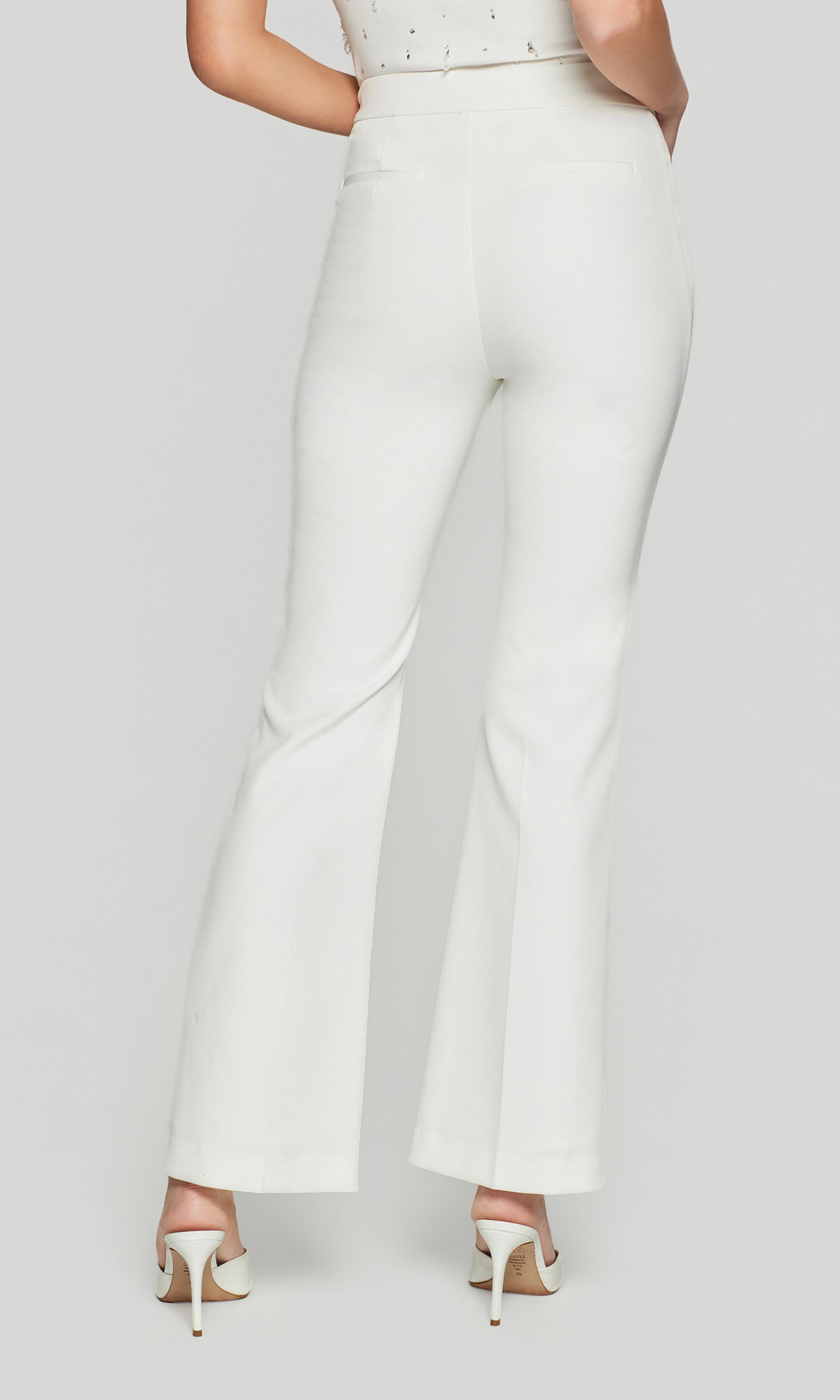 Back view of white high-waist trousers on a person with a light grey background