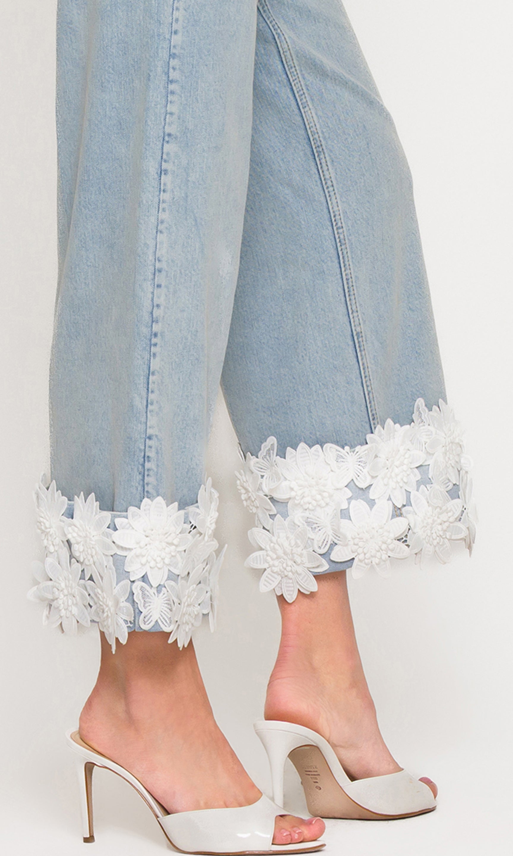 In a close-up detail view, the model wears the Paloma Lace Combo Jeans in light wash denim, spotlighting the dimensional lace cuff trim and clean hem finish.