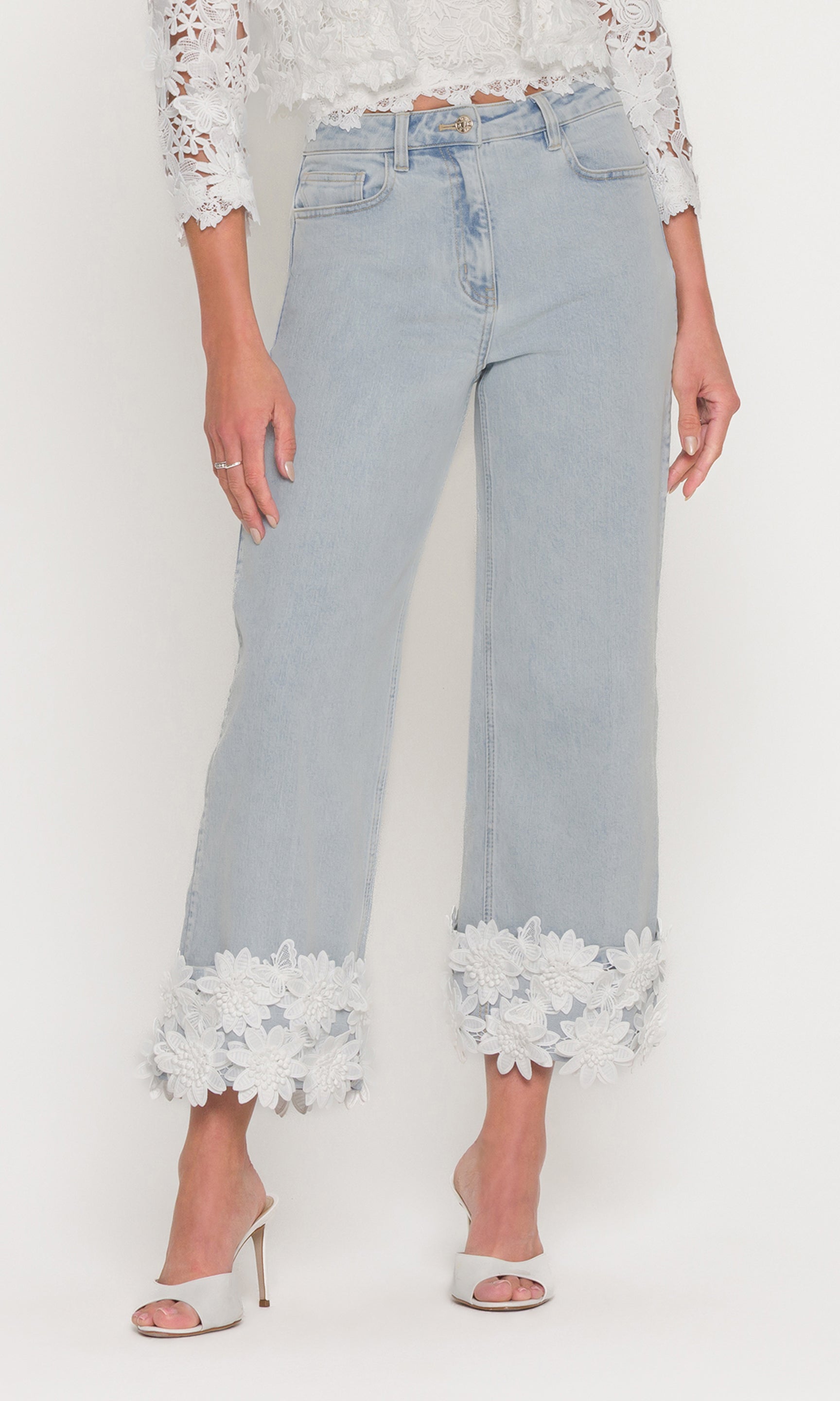 In a front view, the model wears the Paloma Lace Combo Jeans in light wash denim, emphasizing the high-rise fit and lace cuff detail at the ankles.