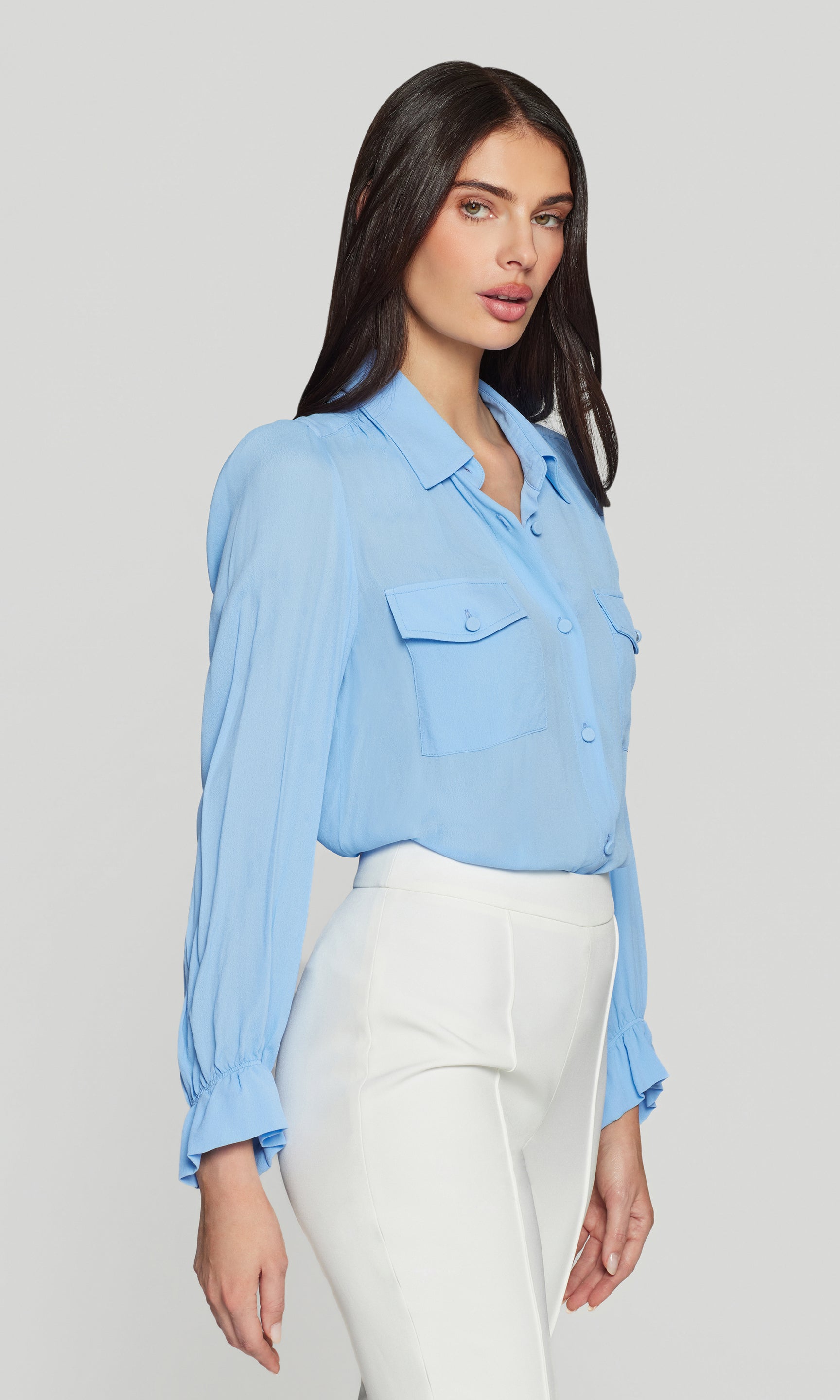 Model wears the Priya Georgette Shirt in light blue in a side view, focusing on the breezy fit, cuff detail, and the smooth tuck at the waist