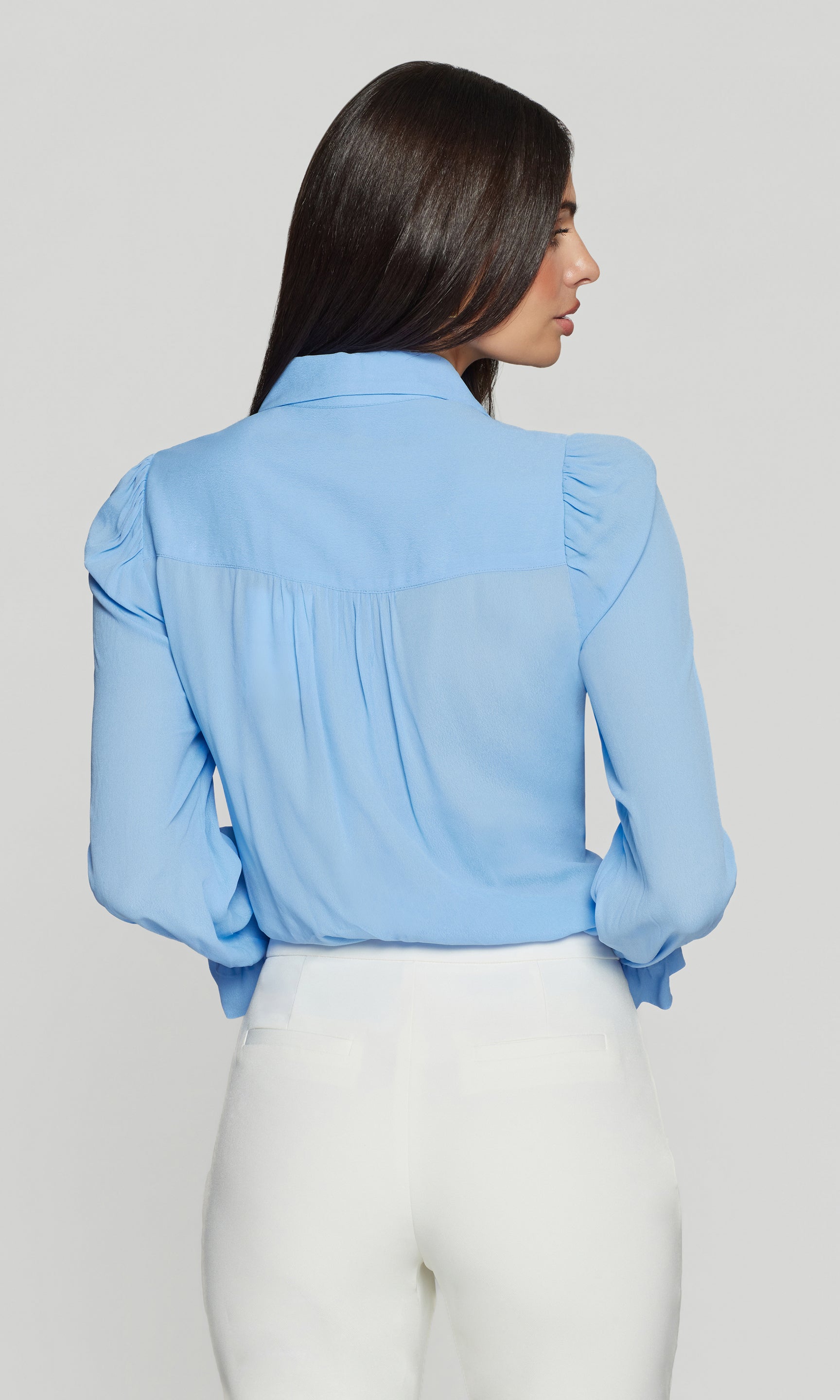 Model wears the Priya Georgette Shirt in light blue in a back view, highlighting the fluid georgette movement and the relaxed shape through the shoulders
