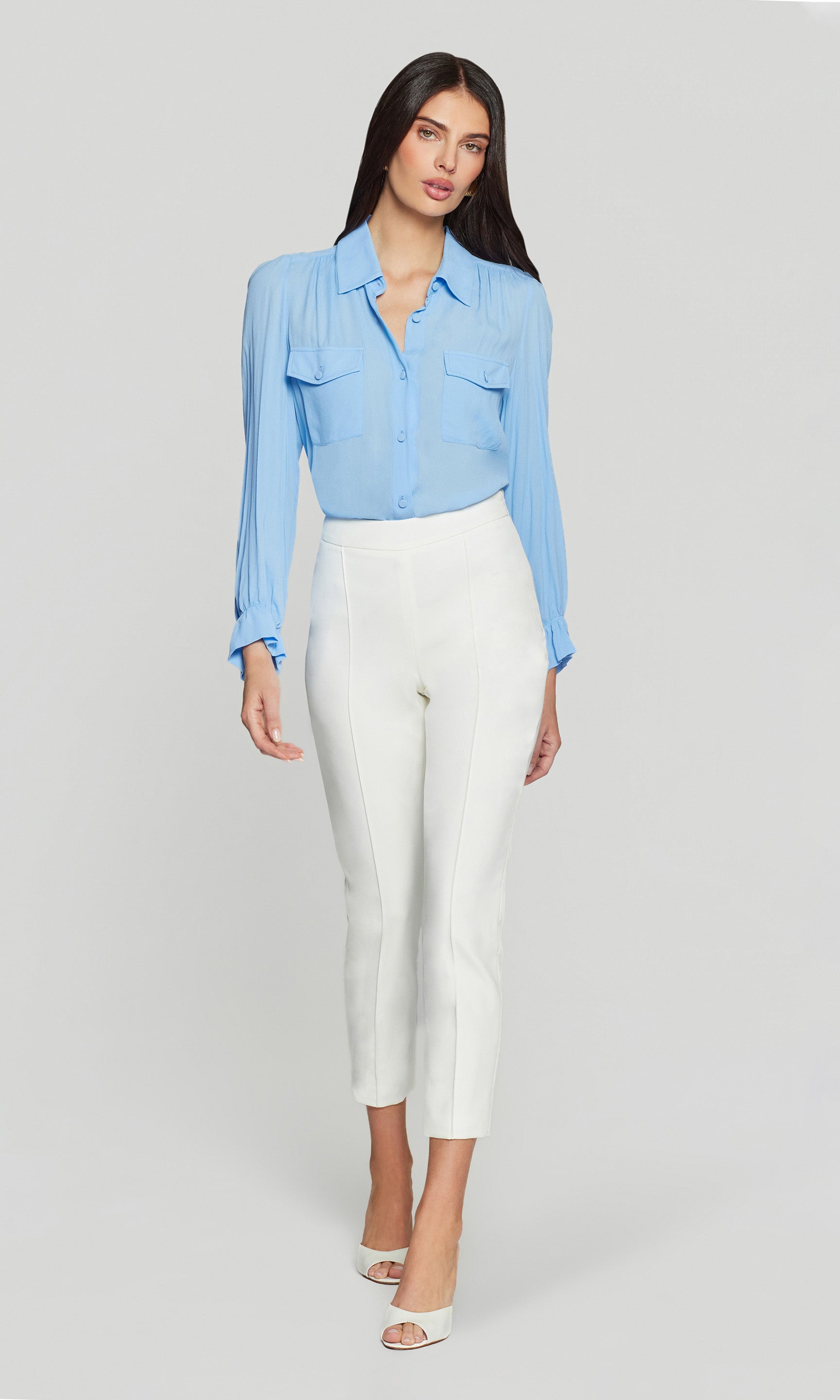 Full body front view of the model wearing the Lonny Crepe Pants in white, styled with a blue blouse and heels to show the streamlined silhouette and crisp cropped length.
