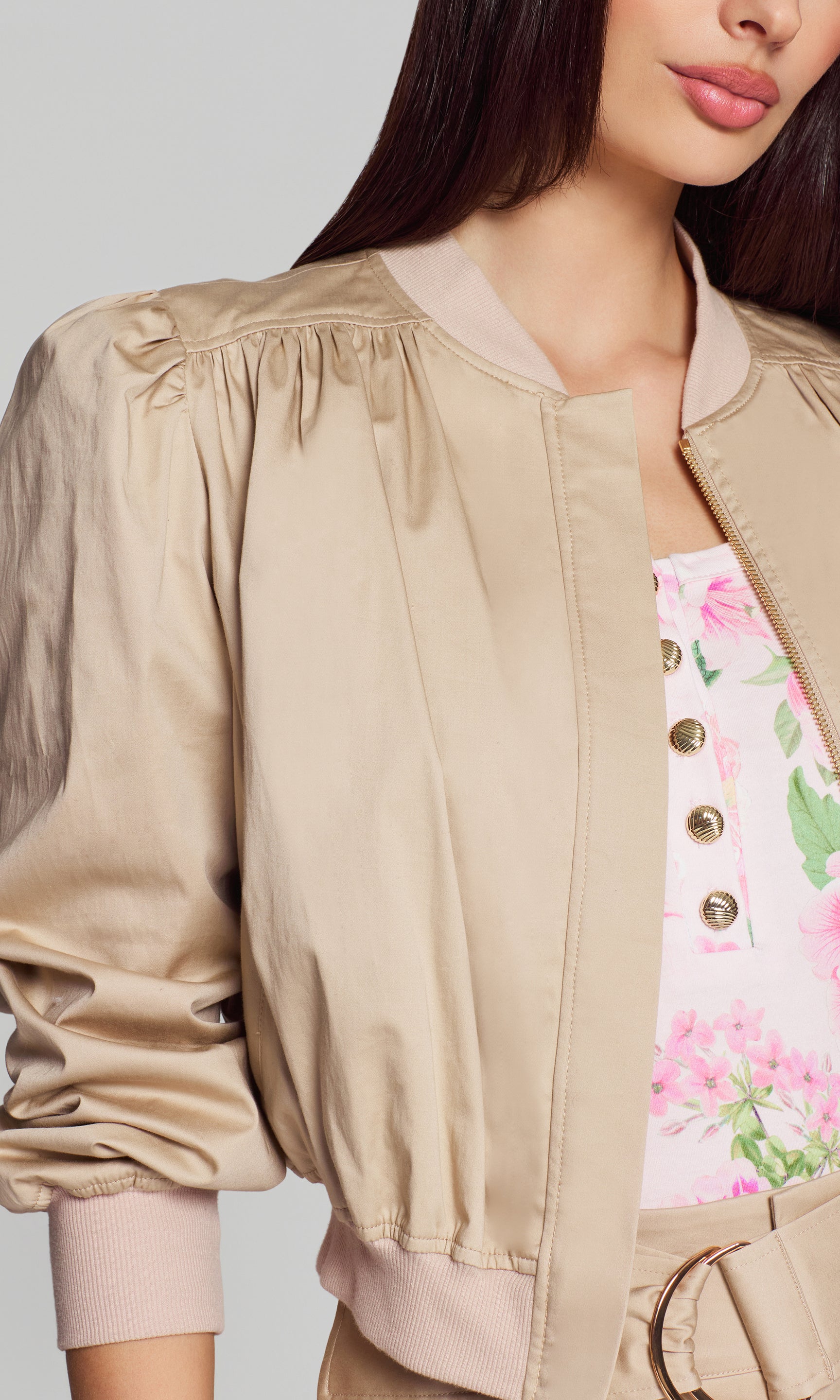 Model wears the light khaki cotton sateen bomber in a close-up front view, highlighting the neckline, shoulder gathering, and sleeve ruching.