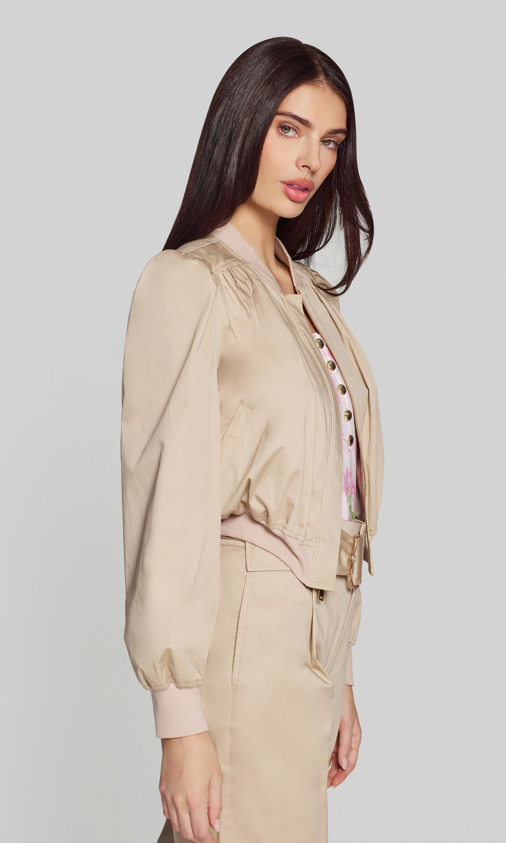 Model wears the light khaki cotton sateen bomber in a side view, showing the cropped length and sleeve volume.