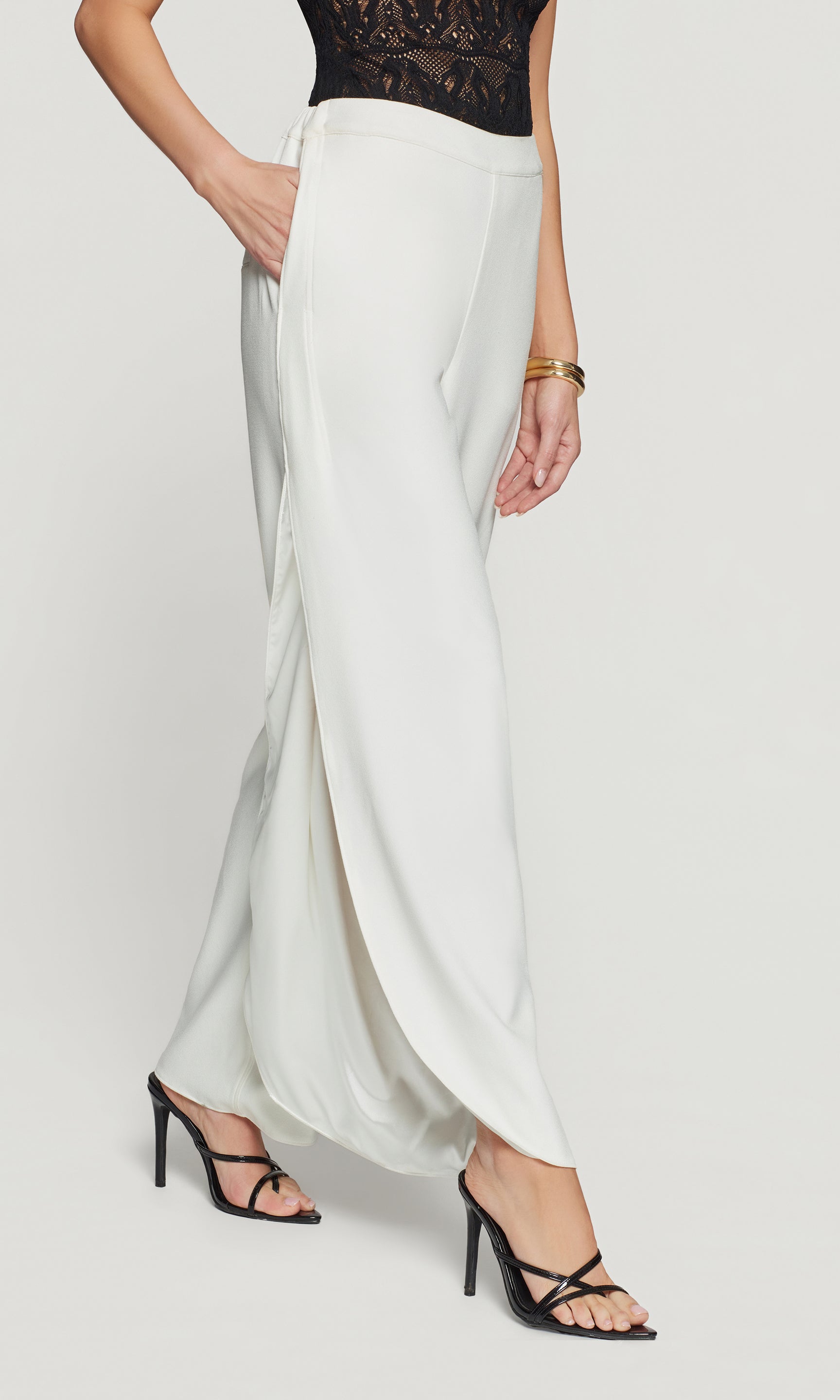 Side view of white flowing pants worn by a person on a white background