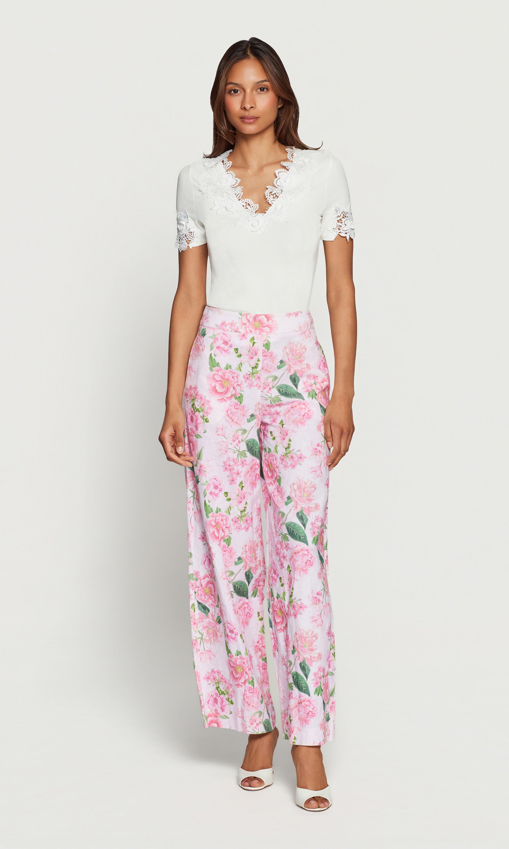 Woman wearing a white top and pink floral pants on a white background