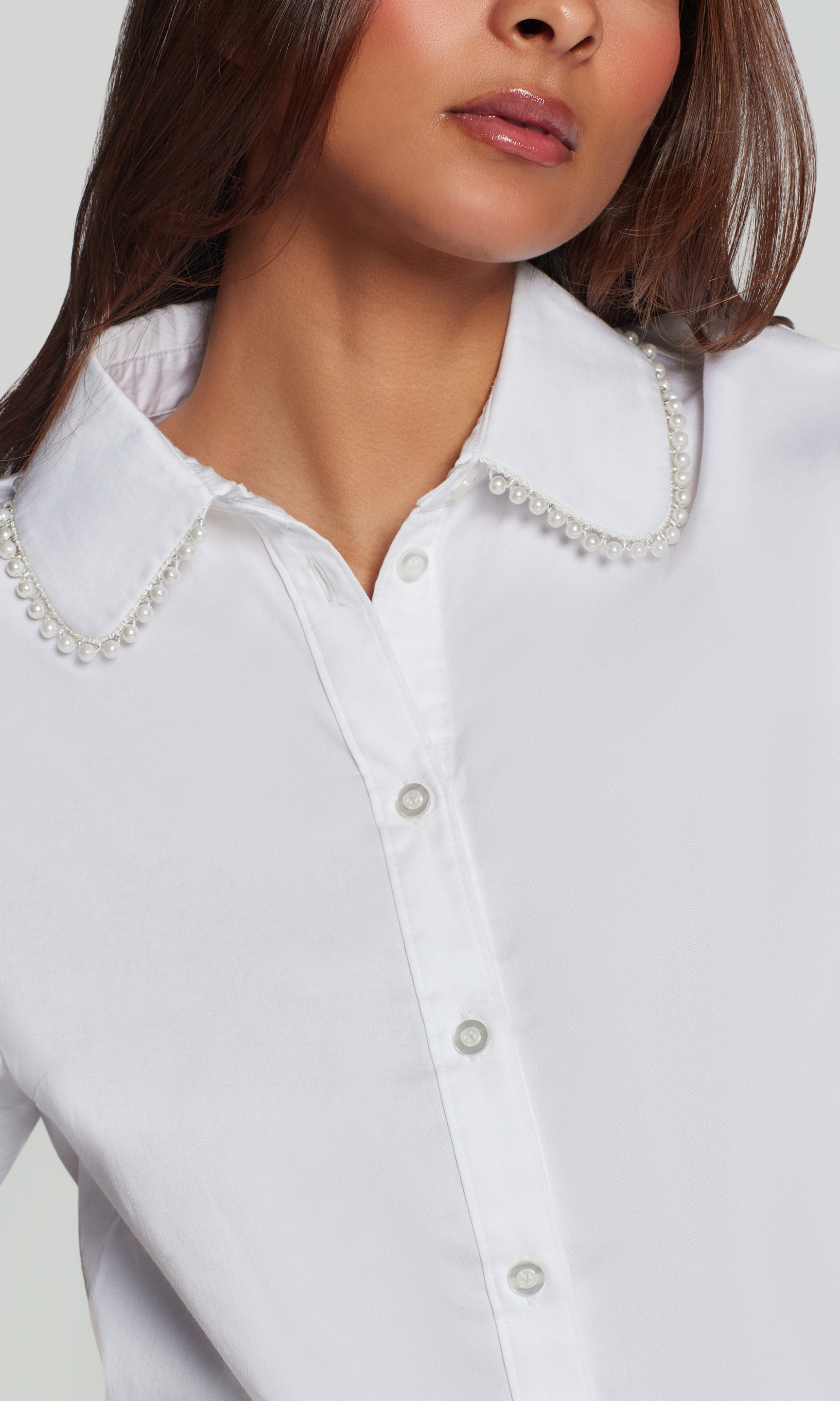 In a close-up detail view, the model wears the Soo Pearl Poplin Shirt in white, focusing on the pearl-trim collar and button placket.
