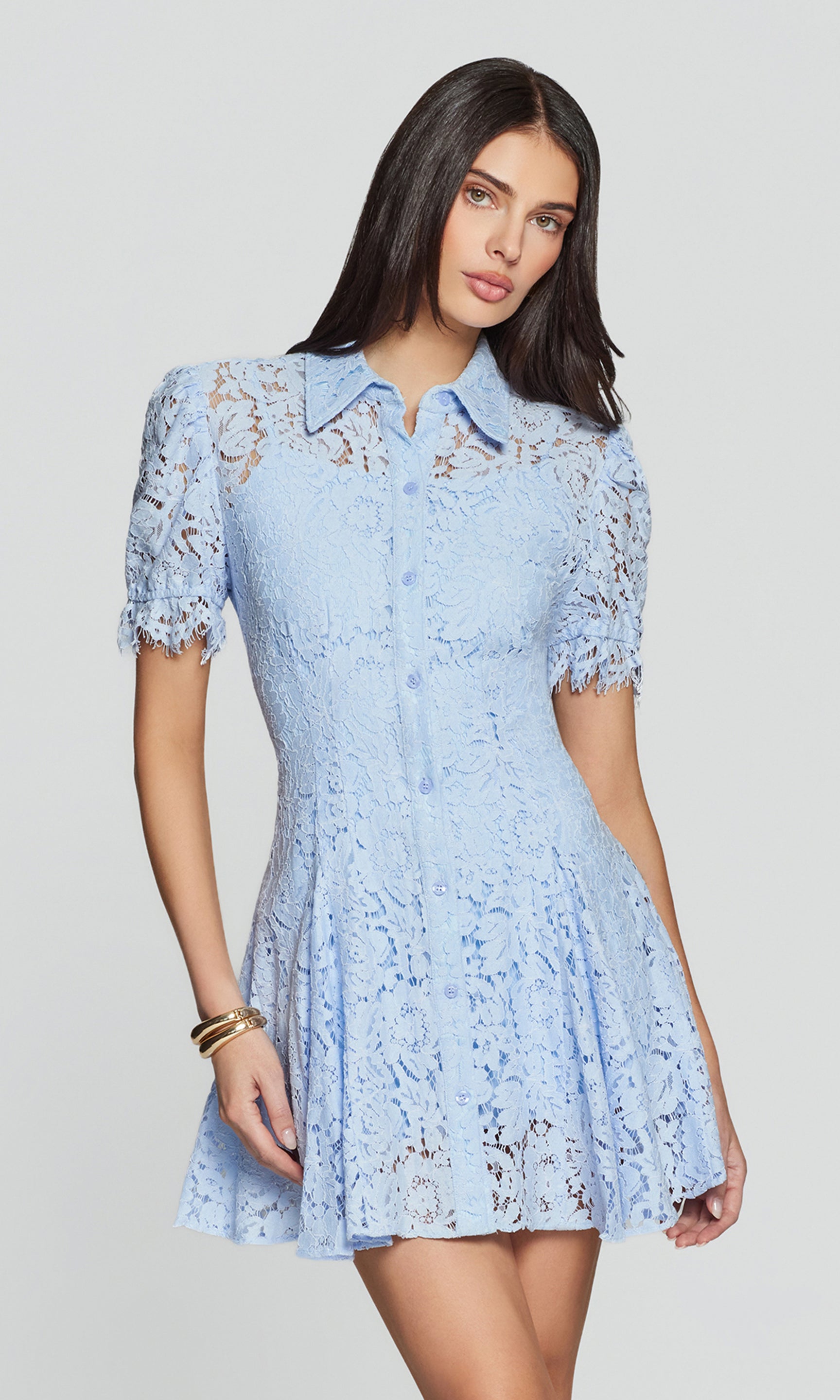 Woman wearing a light blue lace dress against a plain background