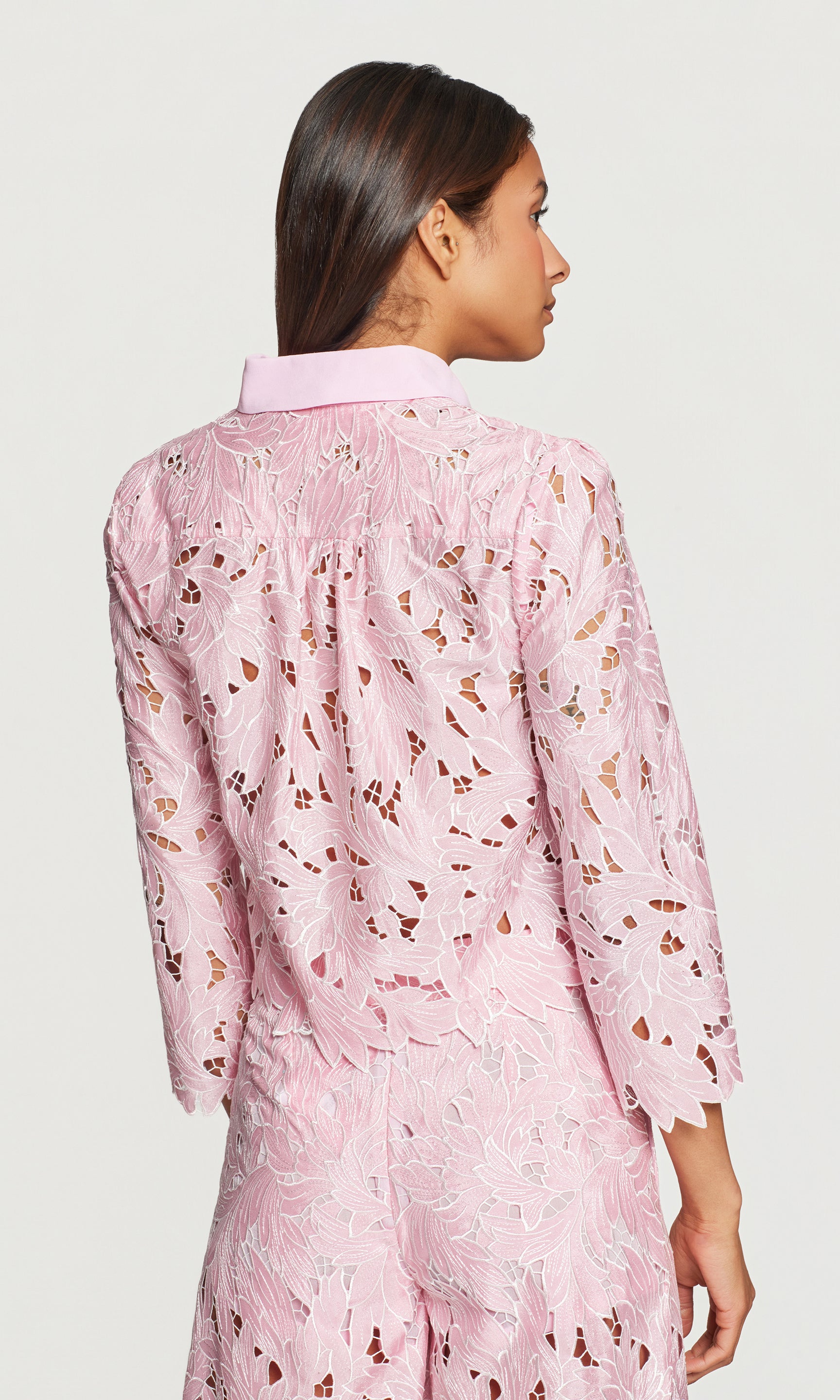 Back view of pink lace blouse on a plain background