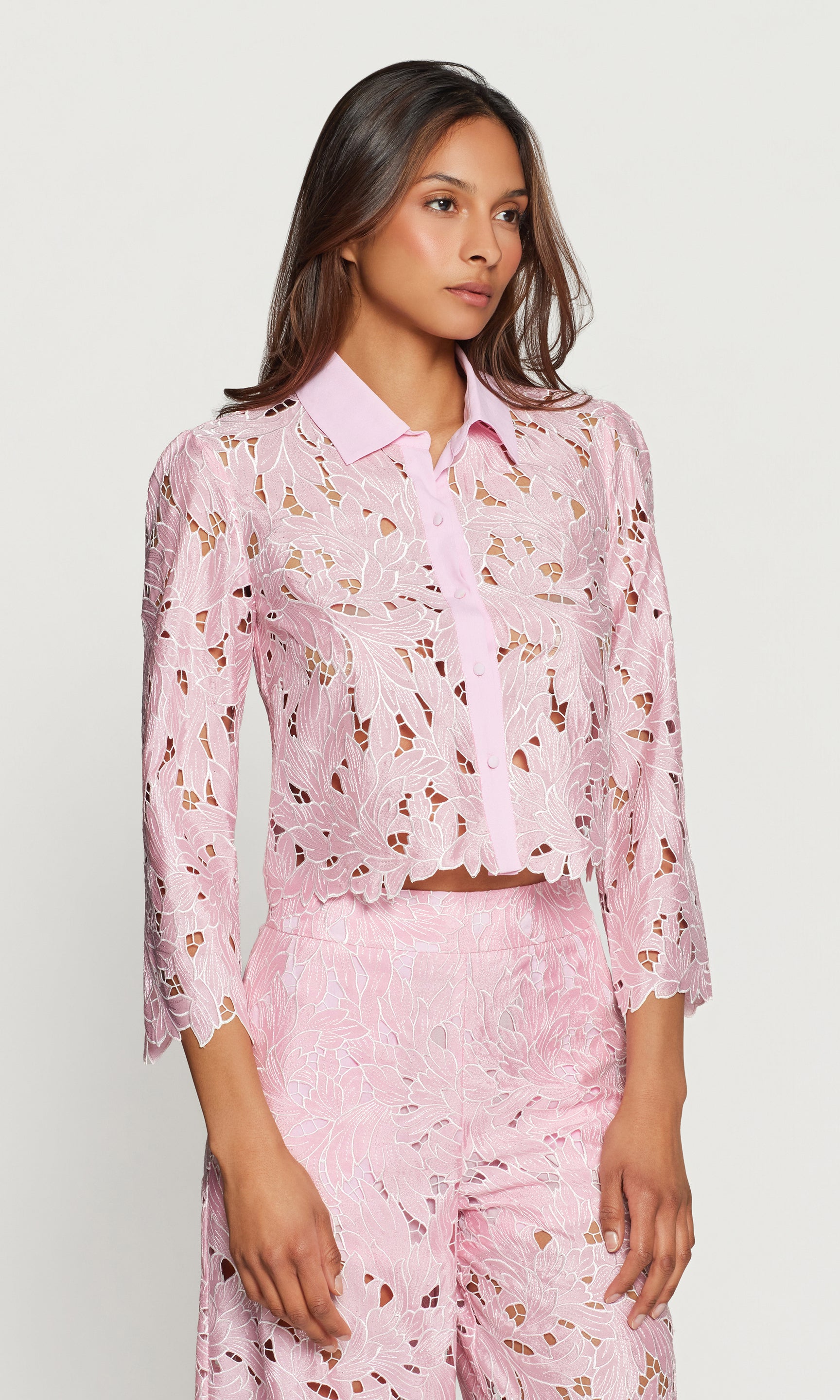 Side view of woman wearing a pink floral blouse on a white background