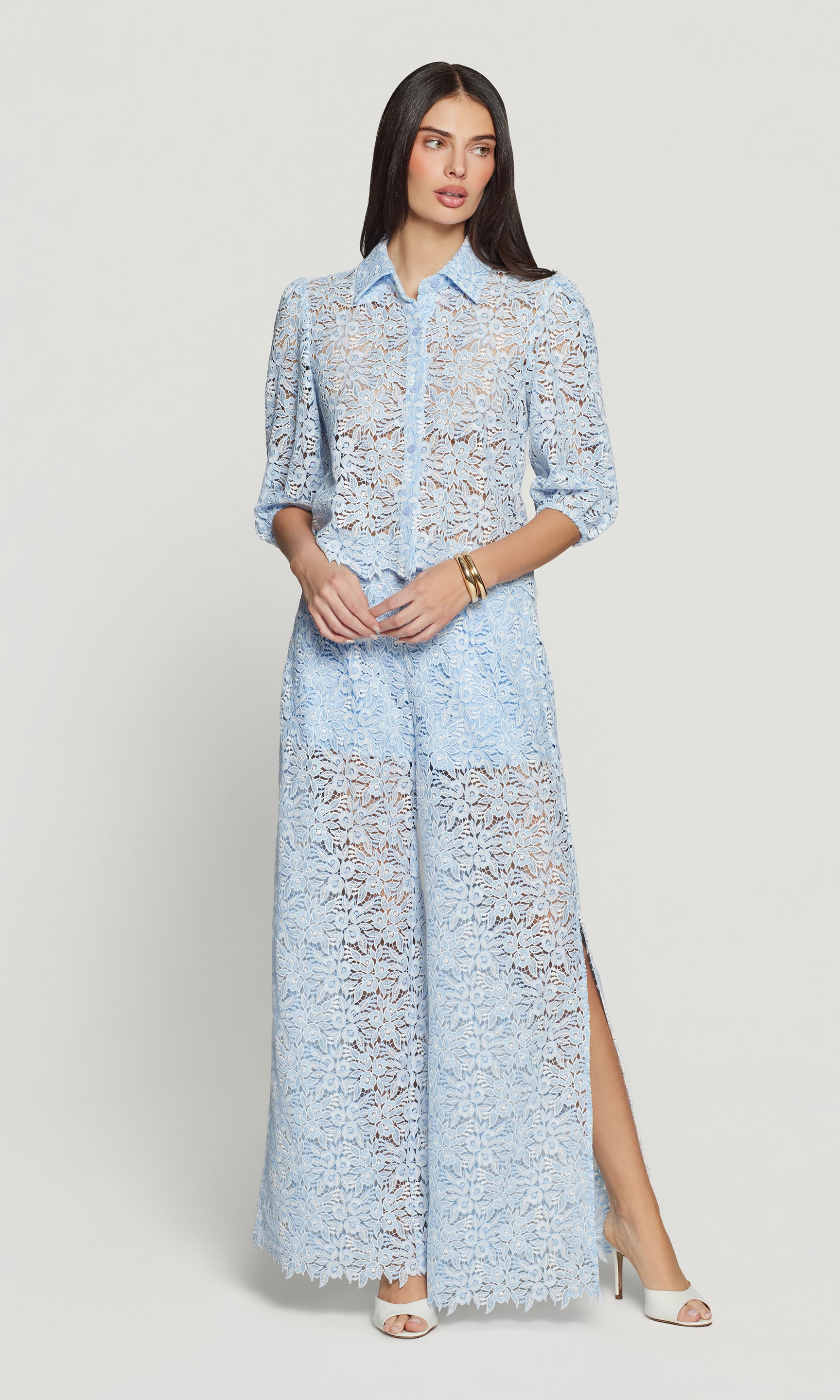 Woman wearing a light blue lace outfit with a high slit on a white background