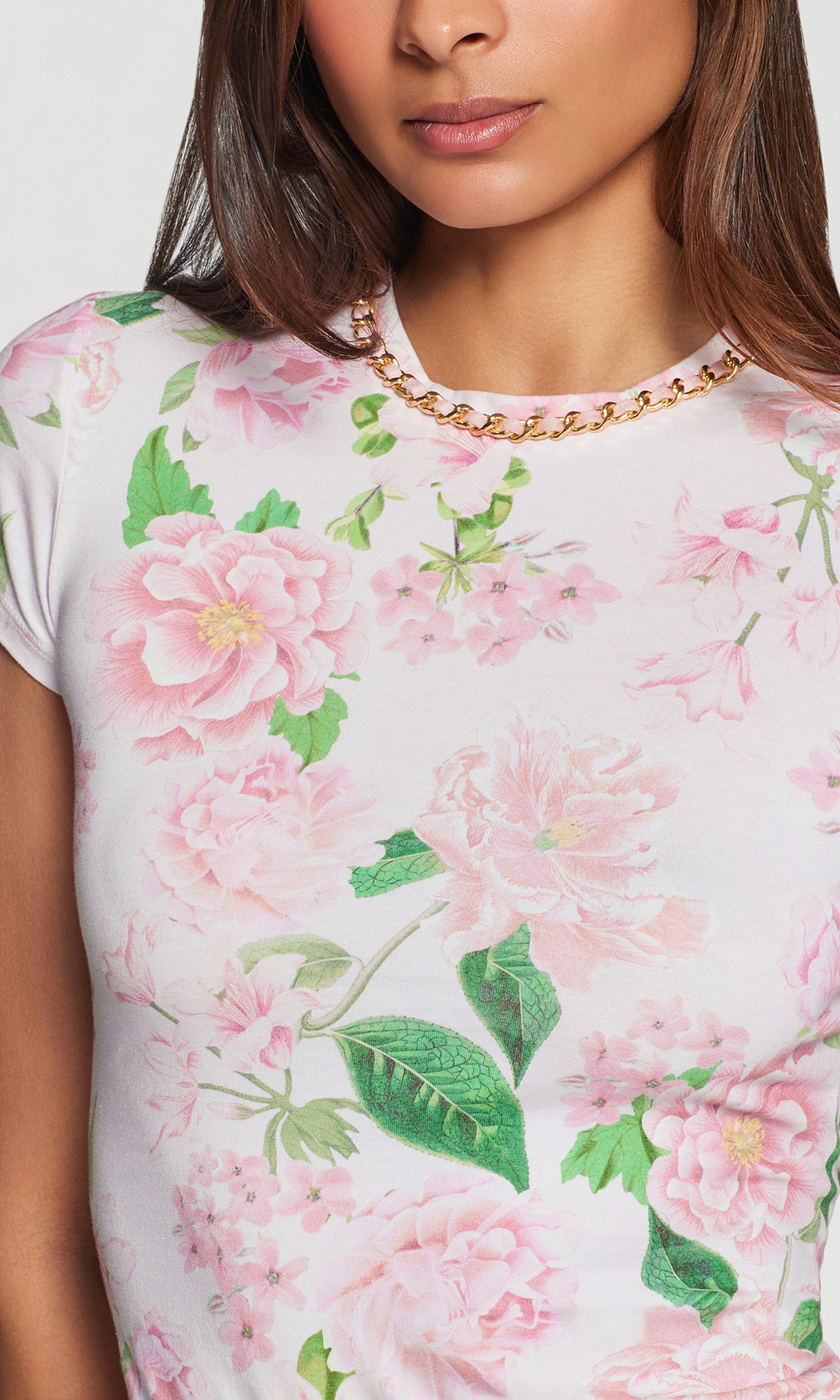 Close-up of a floral-patterned top with pink flowers and green leaves with a chain neckline