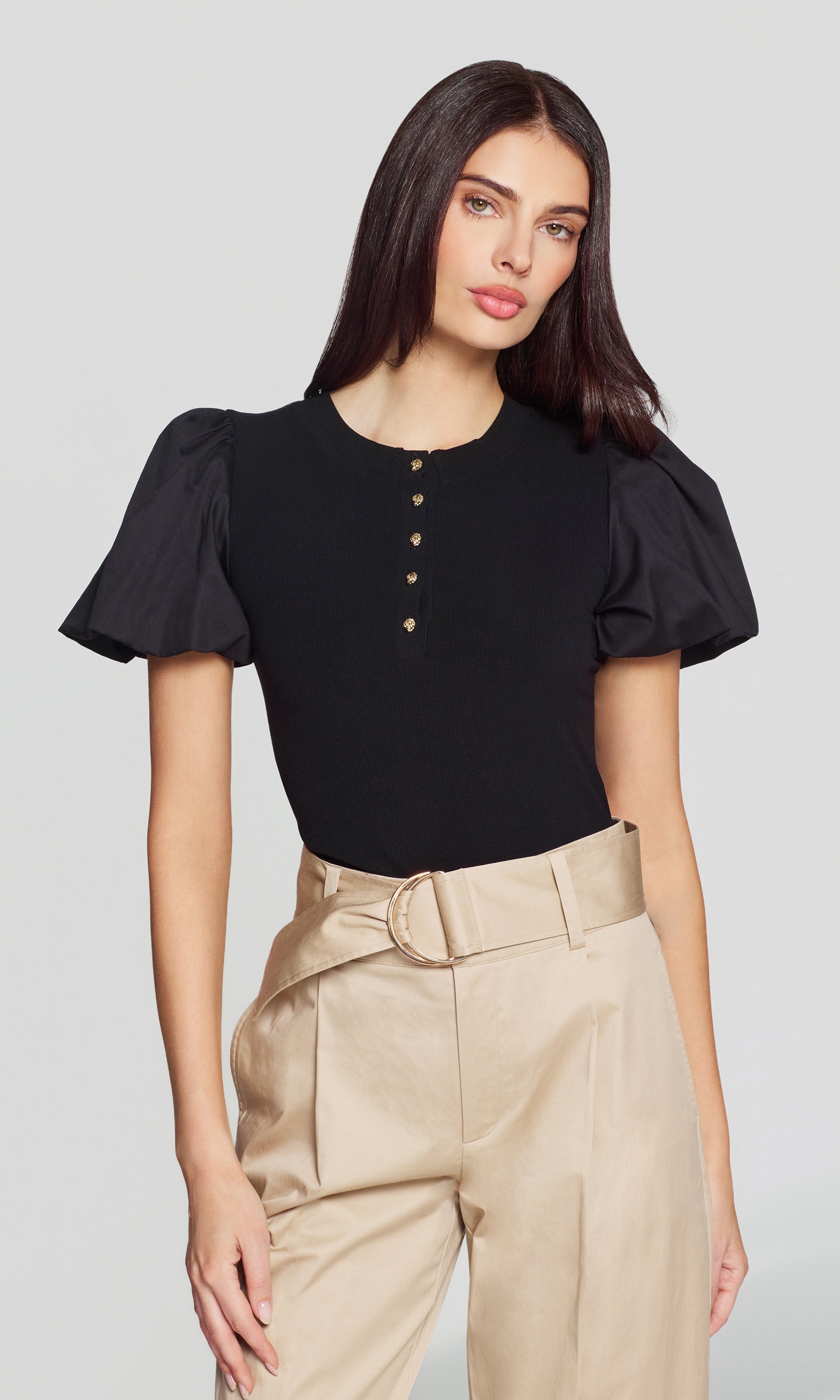 The model wears the Teigan Poplin Combo Top in black in a three-quarter front view, highlighting the puff poplin sleeves and gold-tone button placket on the fitted knit body.
