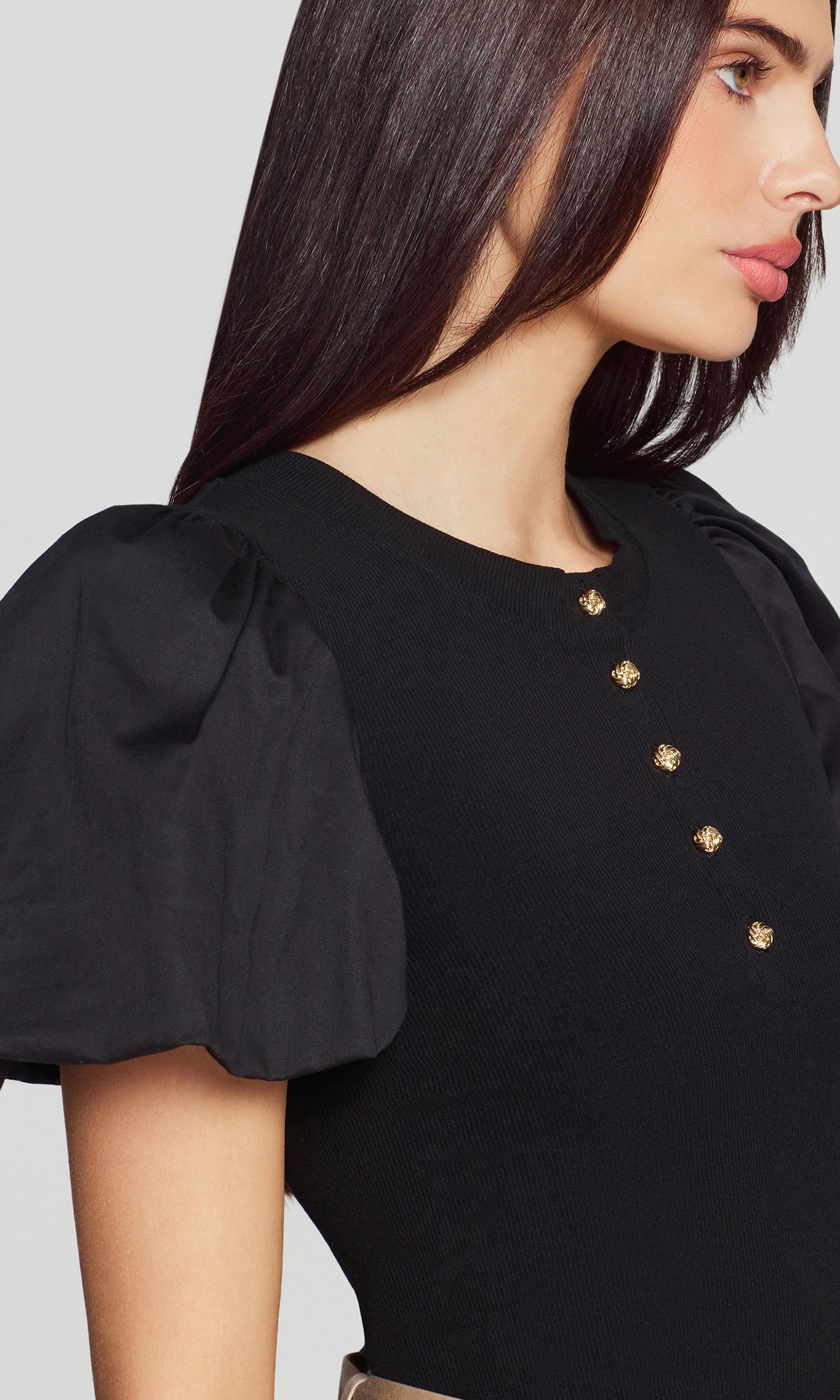 In a close-up three-quarter front view, the model wears the Teigan Poplin Combo Top in black, focusing on the gold-tone buttons and structured puff sleeve detail.