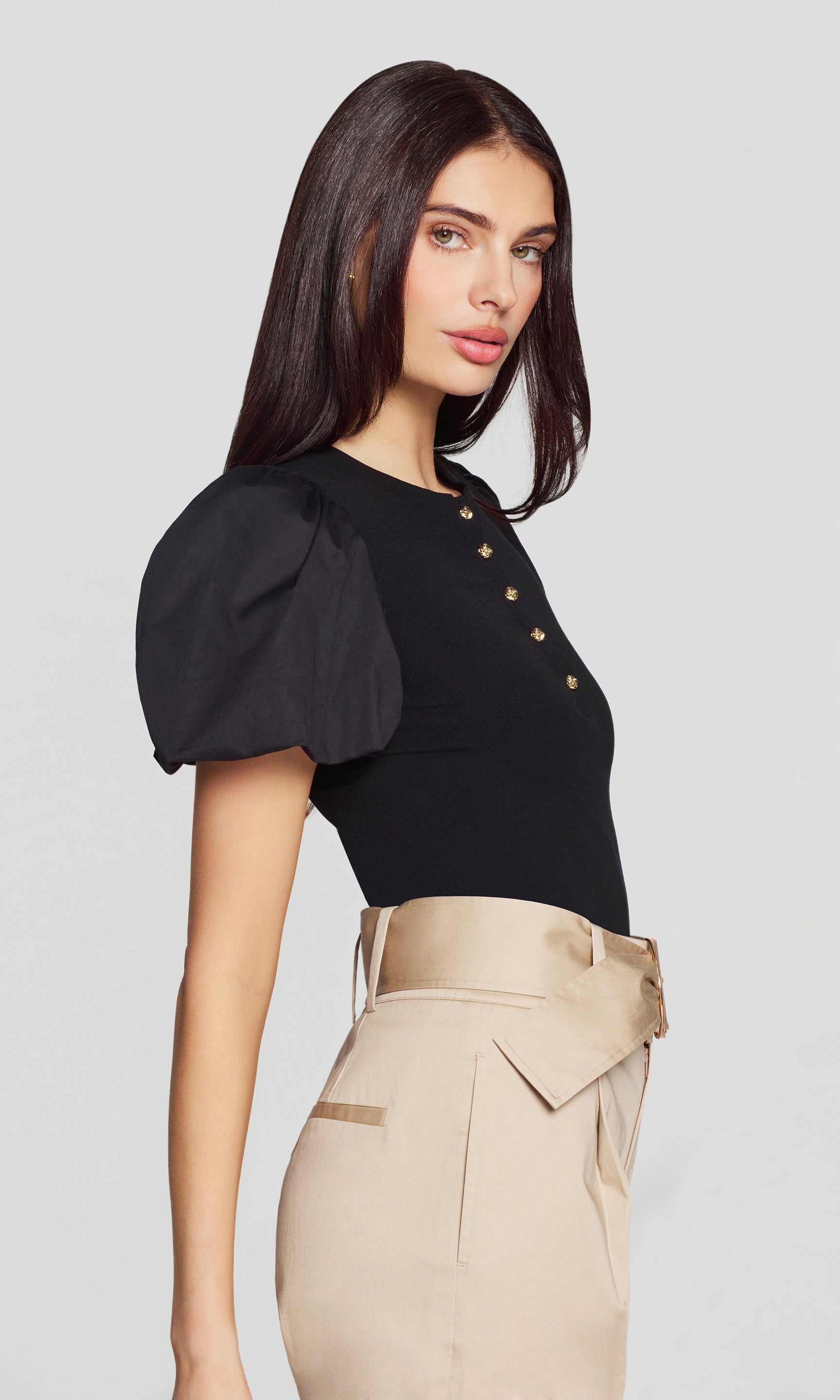 In a side view, the model wears the Teigan Poplin Combo Top in black, emphasizing the sculpted puff sleeve shape and sleek, flattering fit.