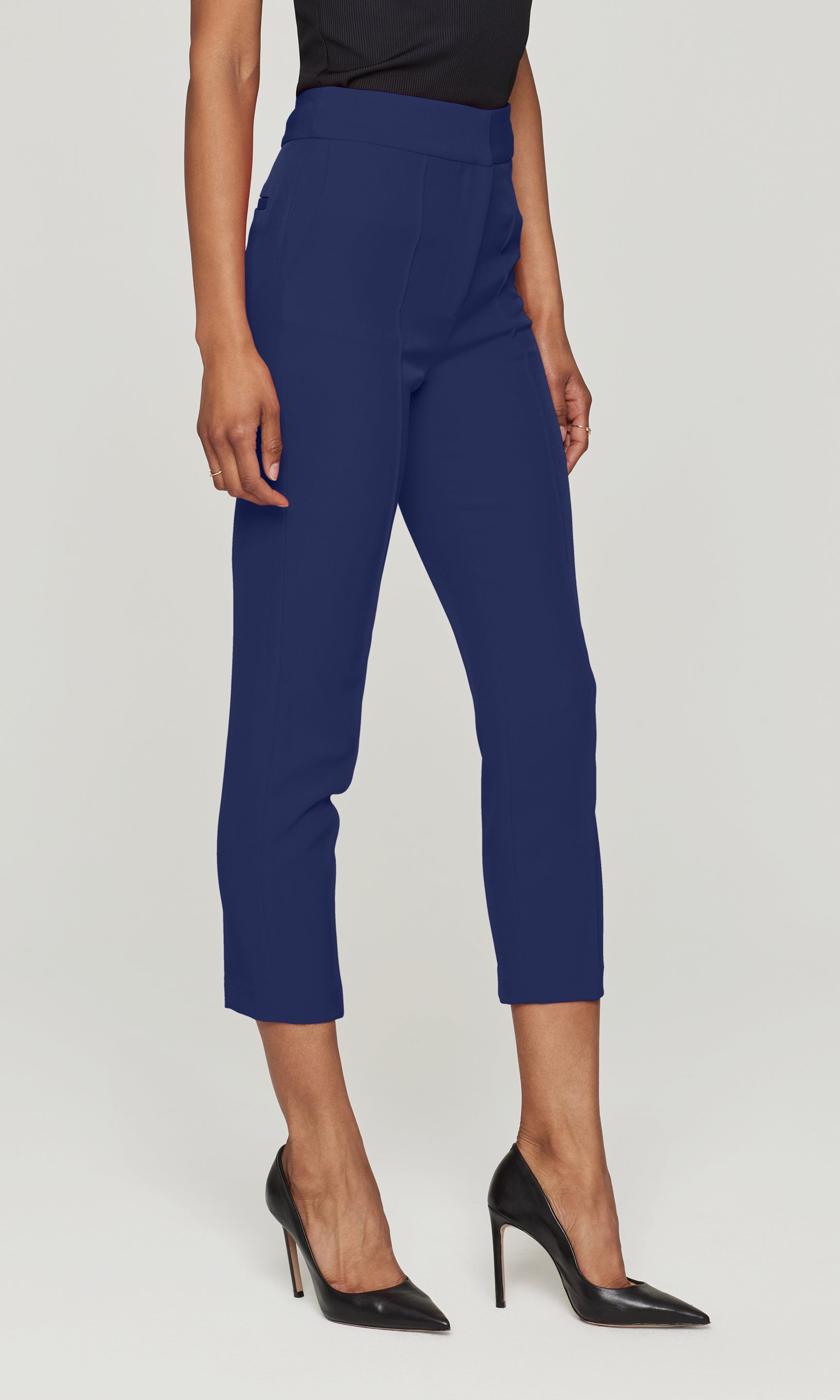 Side view of person wearing blue pants and black high heels on a white background