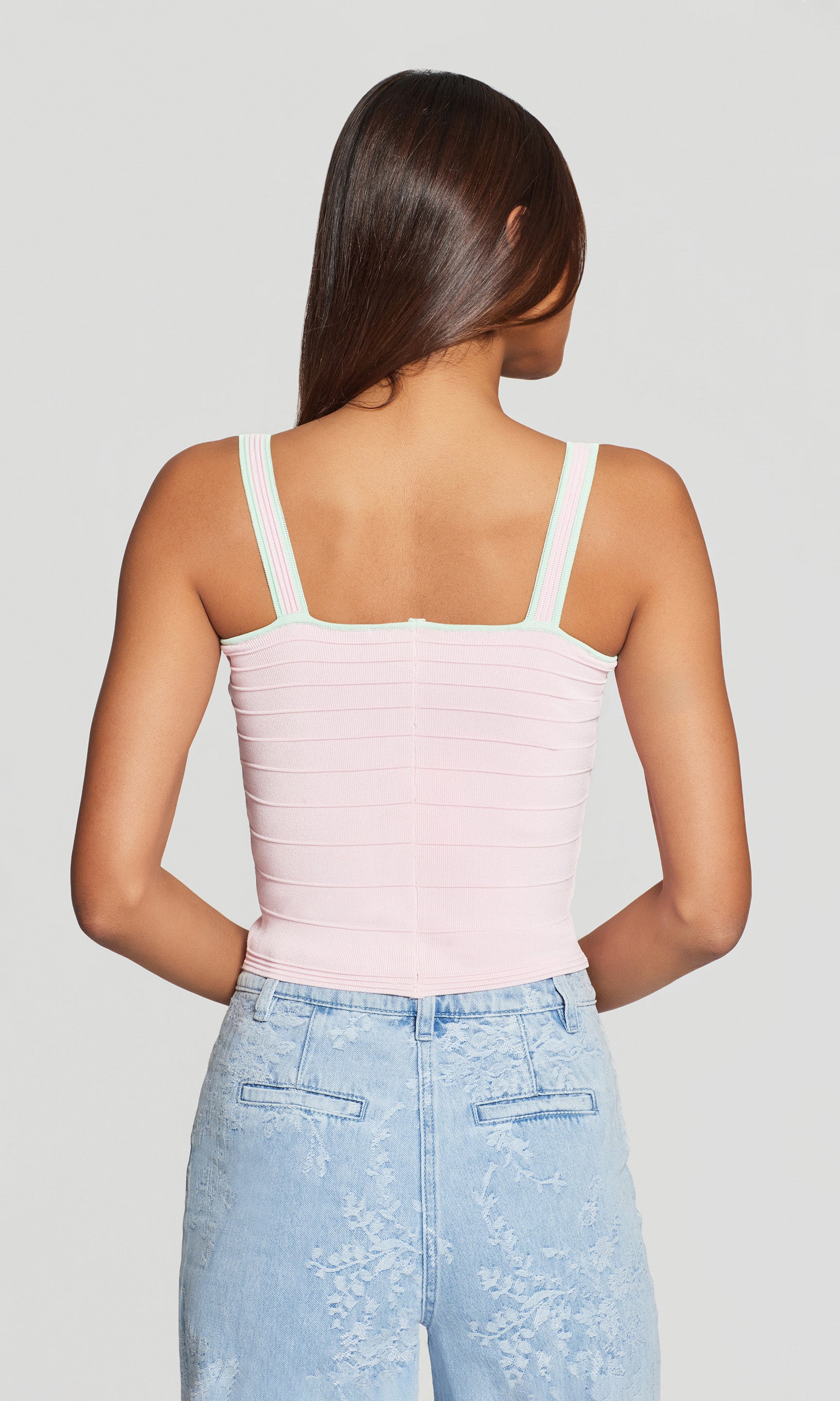 The model wears the Vivi Bandage Tank in pink with mint trim in a close-up three-quarter view, styled under the matching cardigan for a polished set moment.