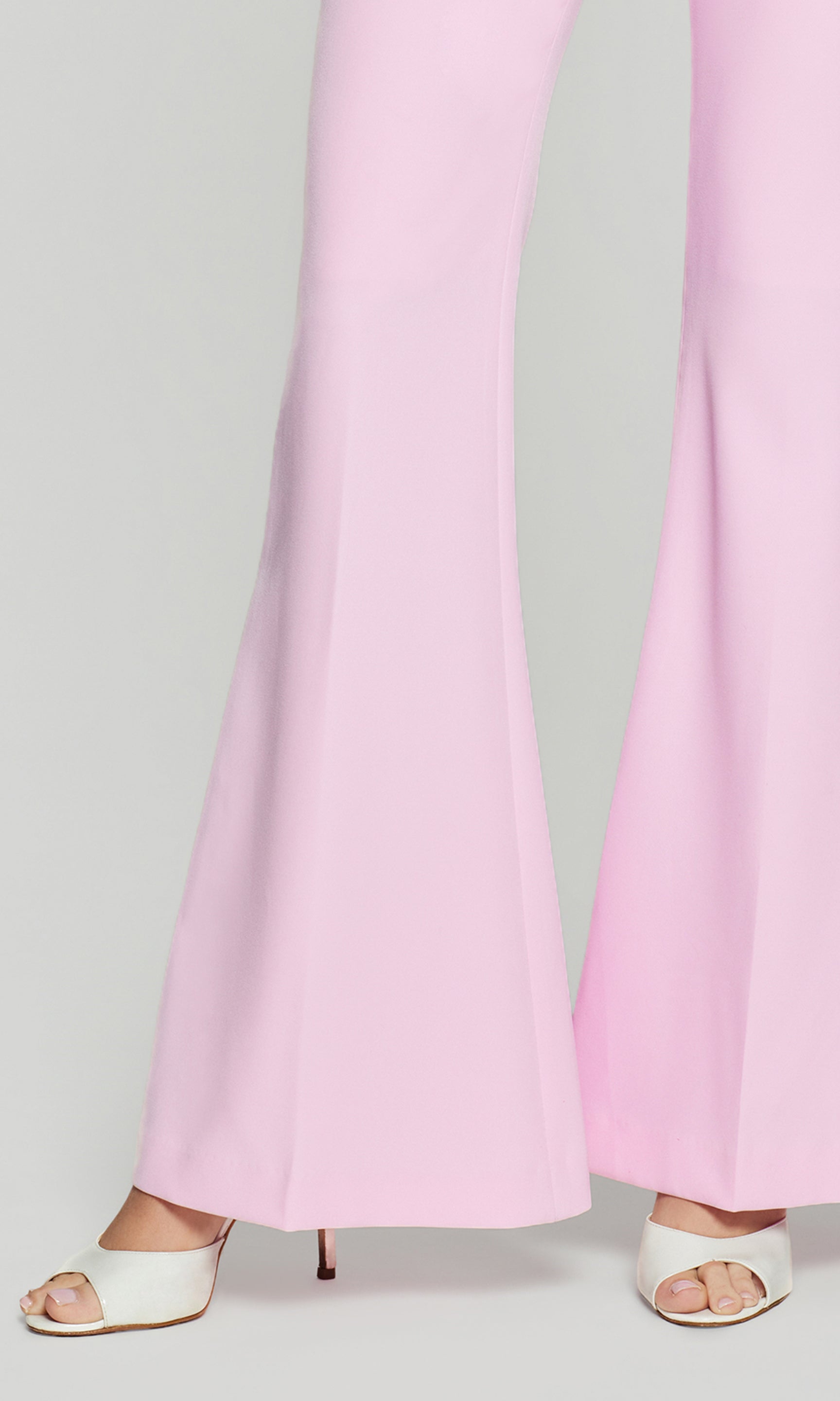 Close-up of pink pants flared leg worn by a person on a light gray background