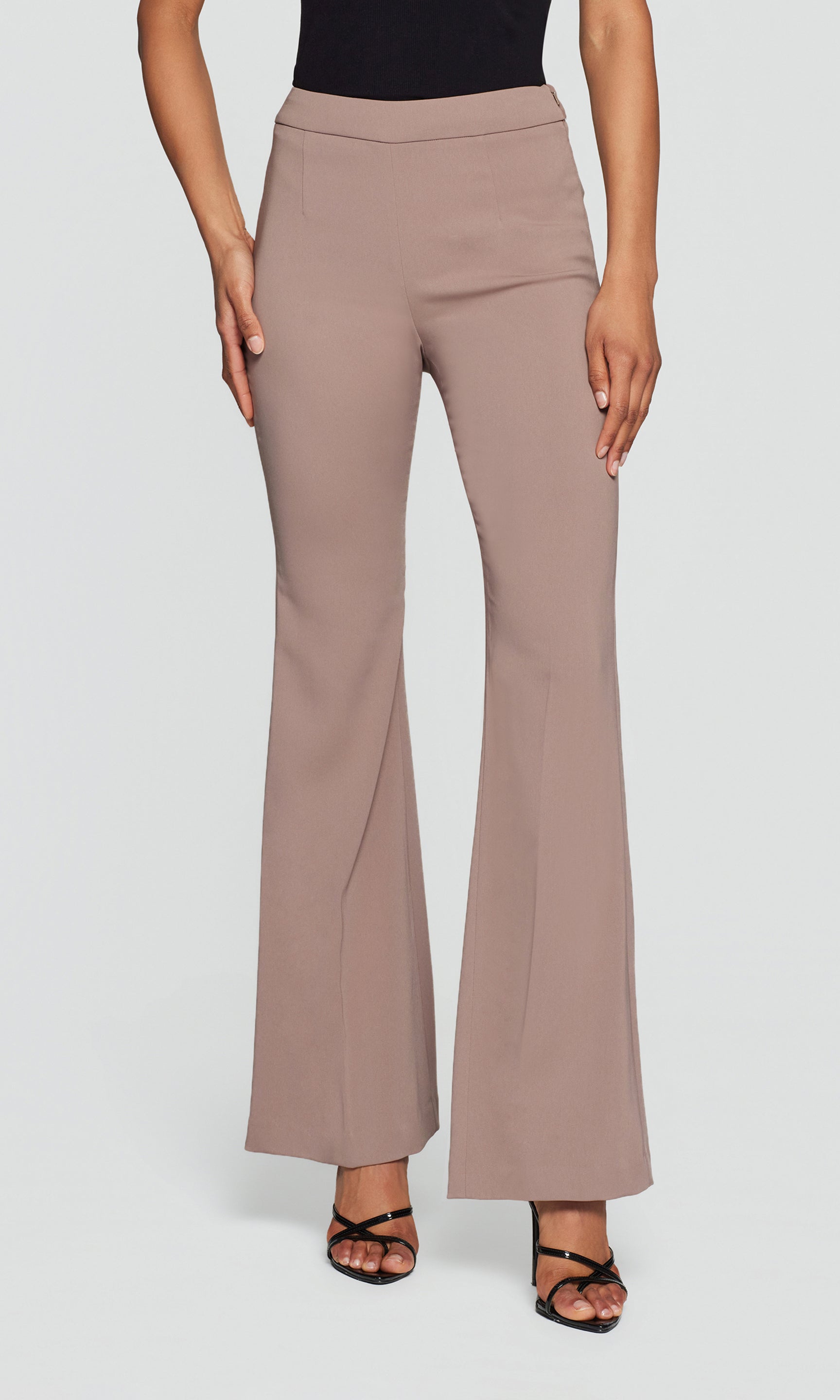 Model wears the taupe Wesley Crepe Pants in a studio front view, showing the clean waistband and slim flare fit.