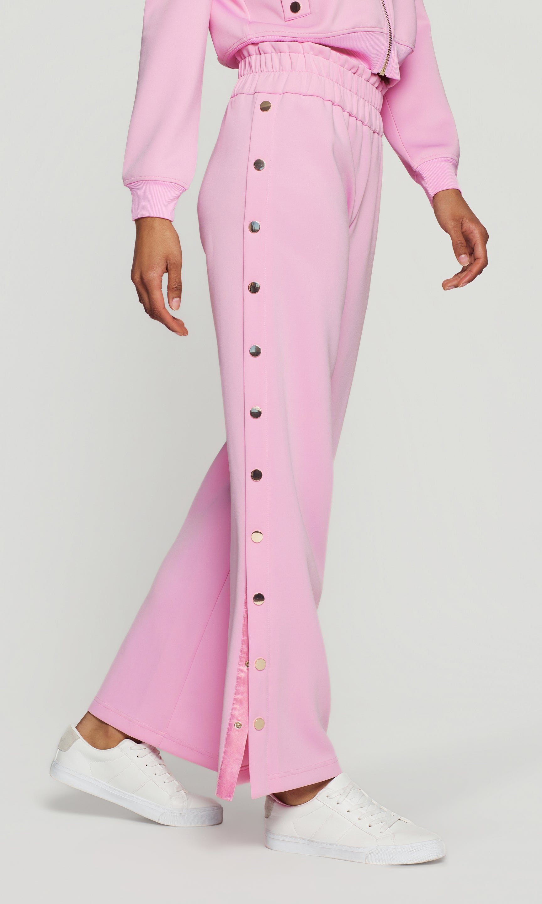 Person wearing a pink outfit with button details on a white background
