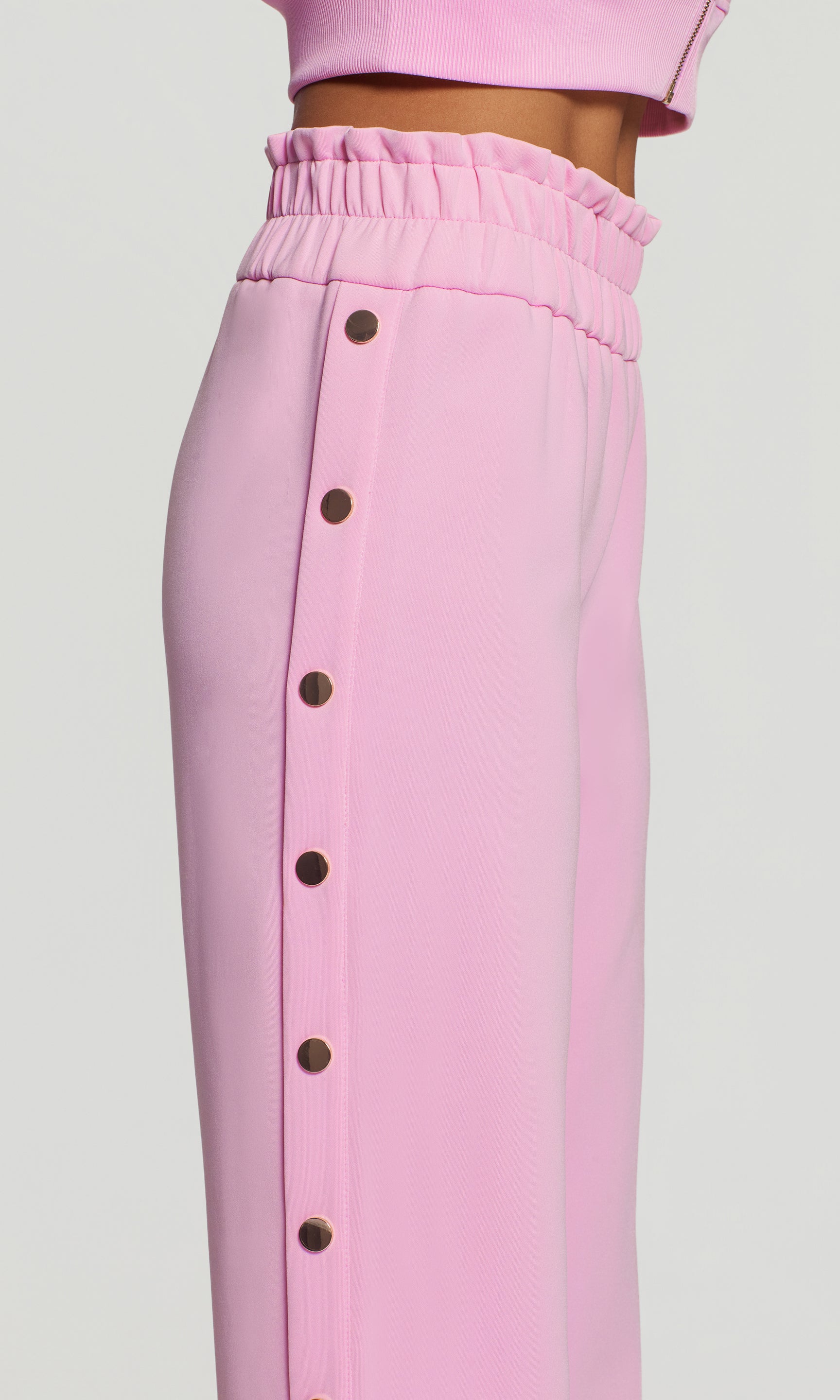 Close-up of pink pants with button details on a light gray background