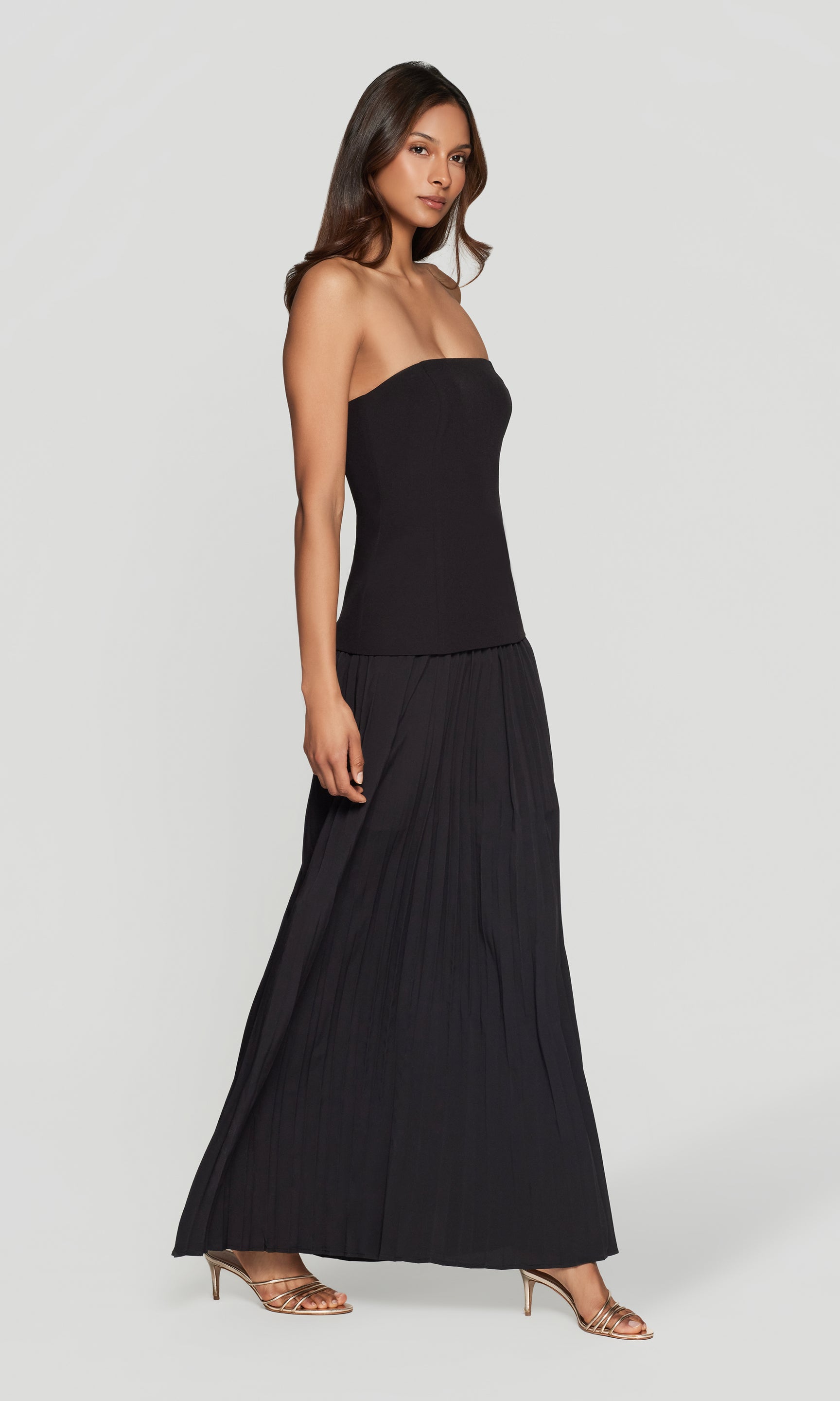 Side view of woman wearing a black strapless dress on a white background