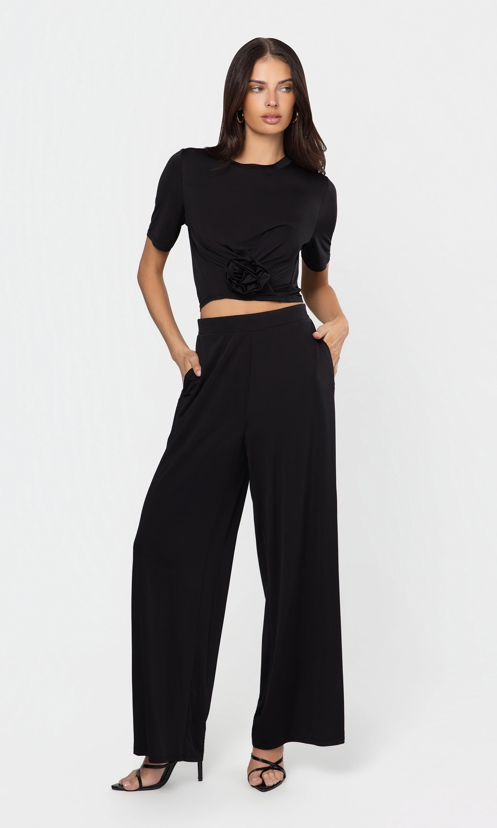 Woman wearing a black outfit with a top and wide-leg pants on a white background