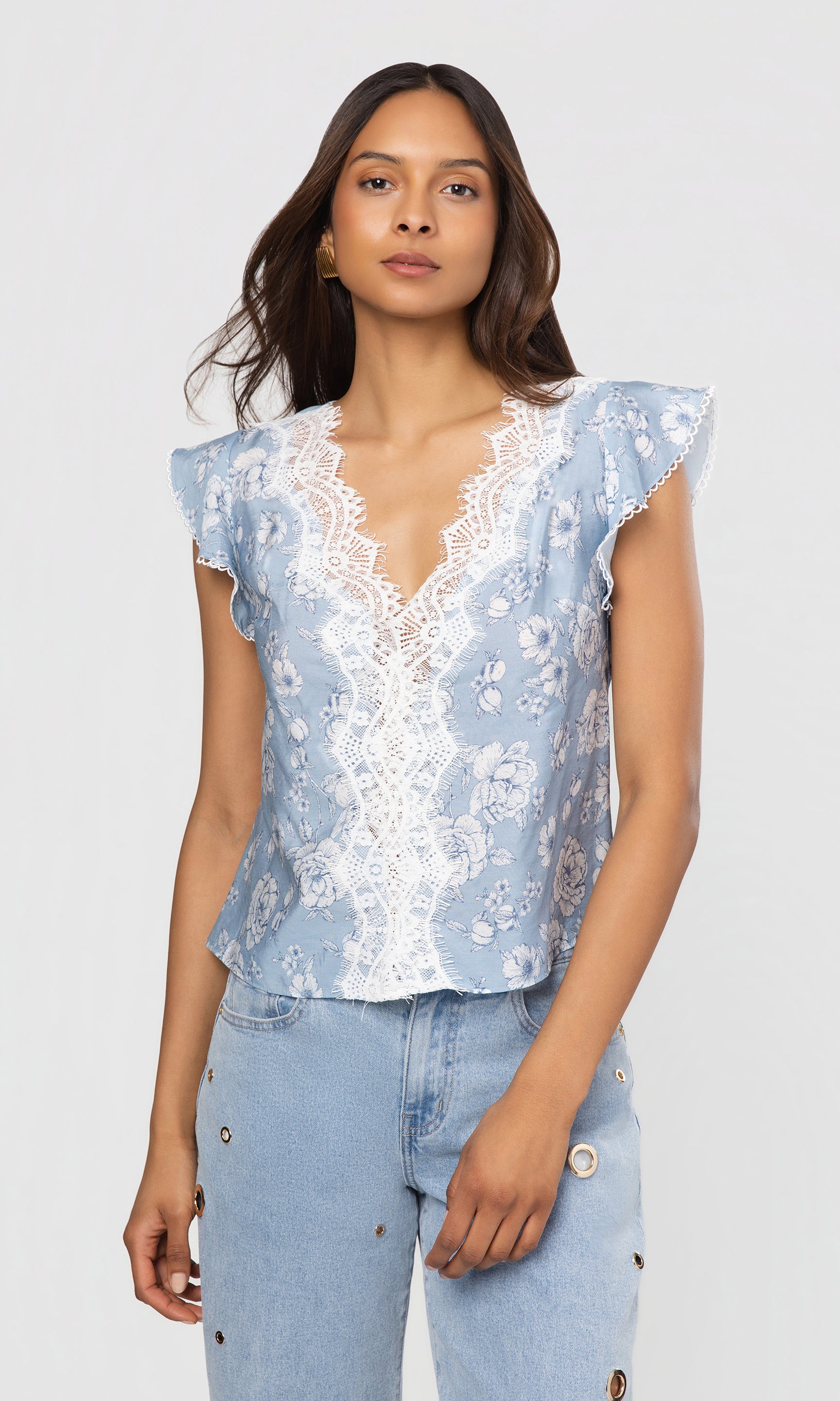 Woman wearing a light blue floral blouse with lace details on a white background