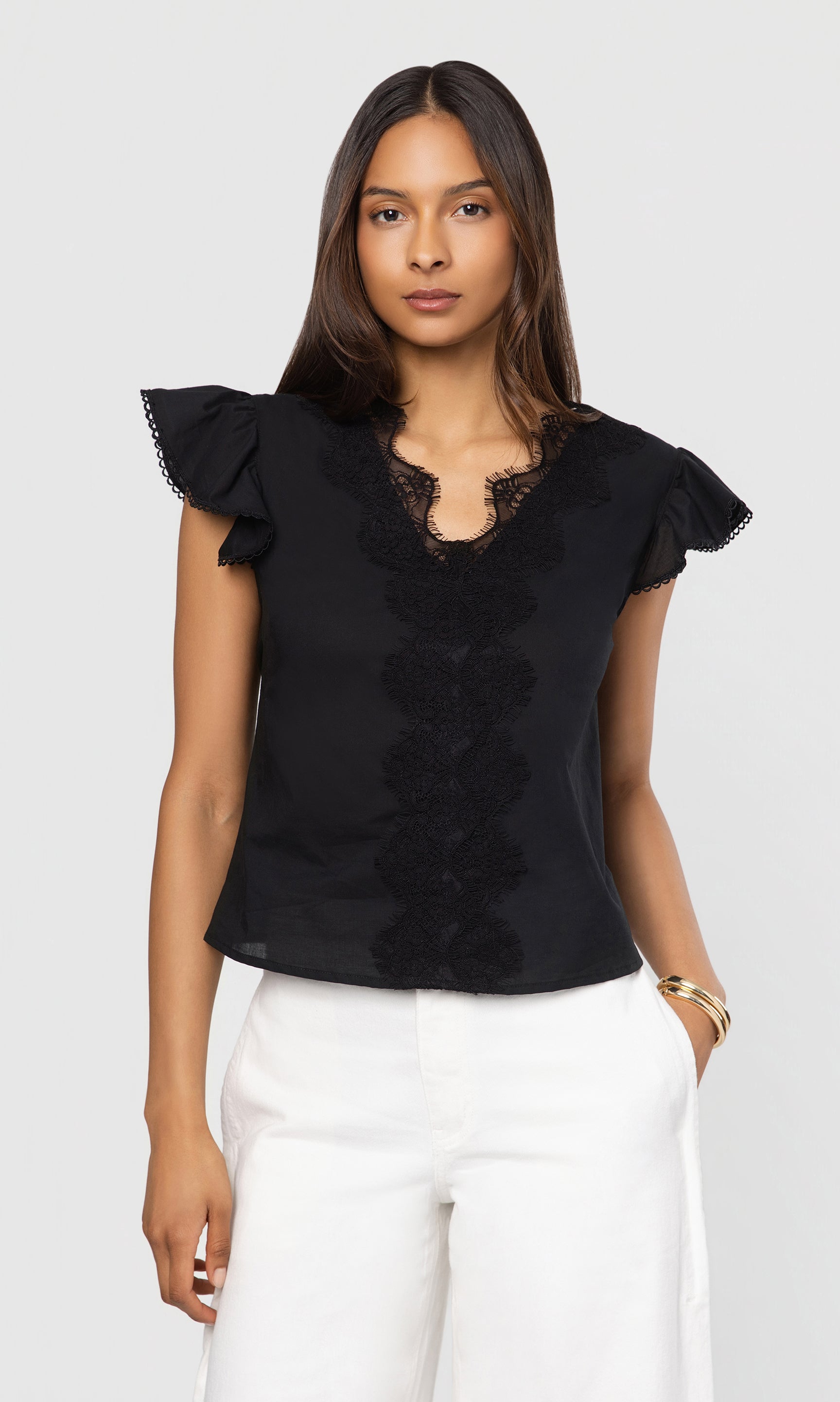 Woman wearing a black blouse with ruffled sleeves and lace details on a white background