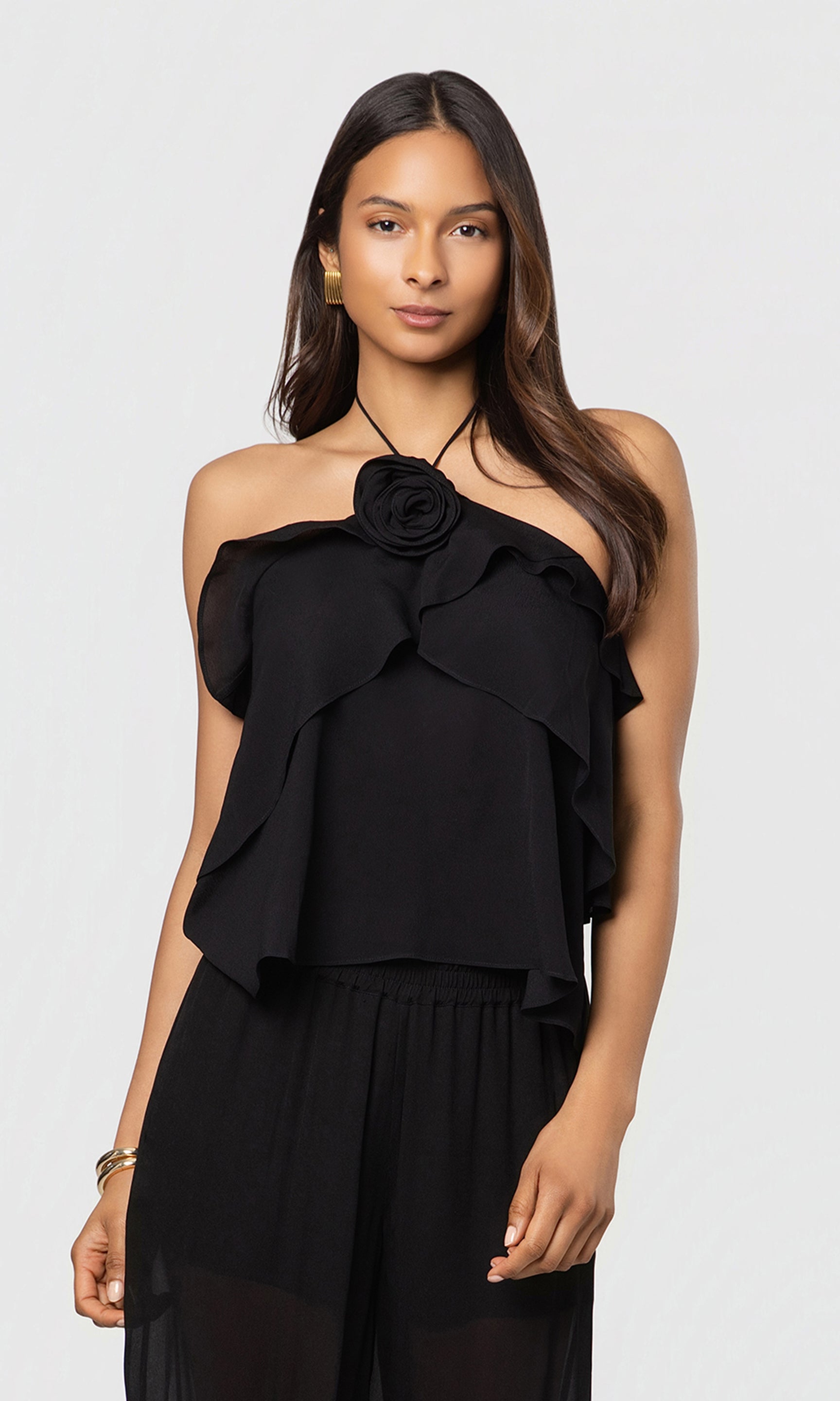Woman wearing a black halter top with floral detail on a white background