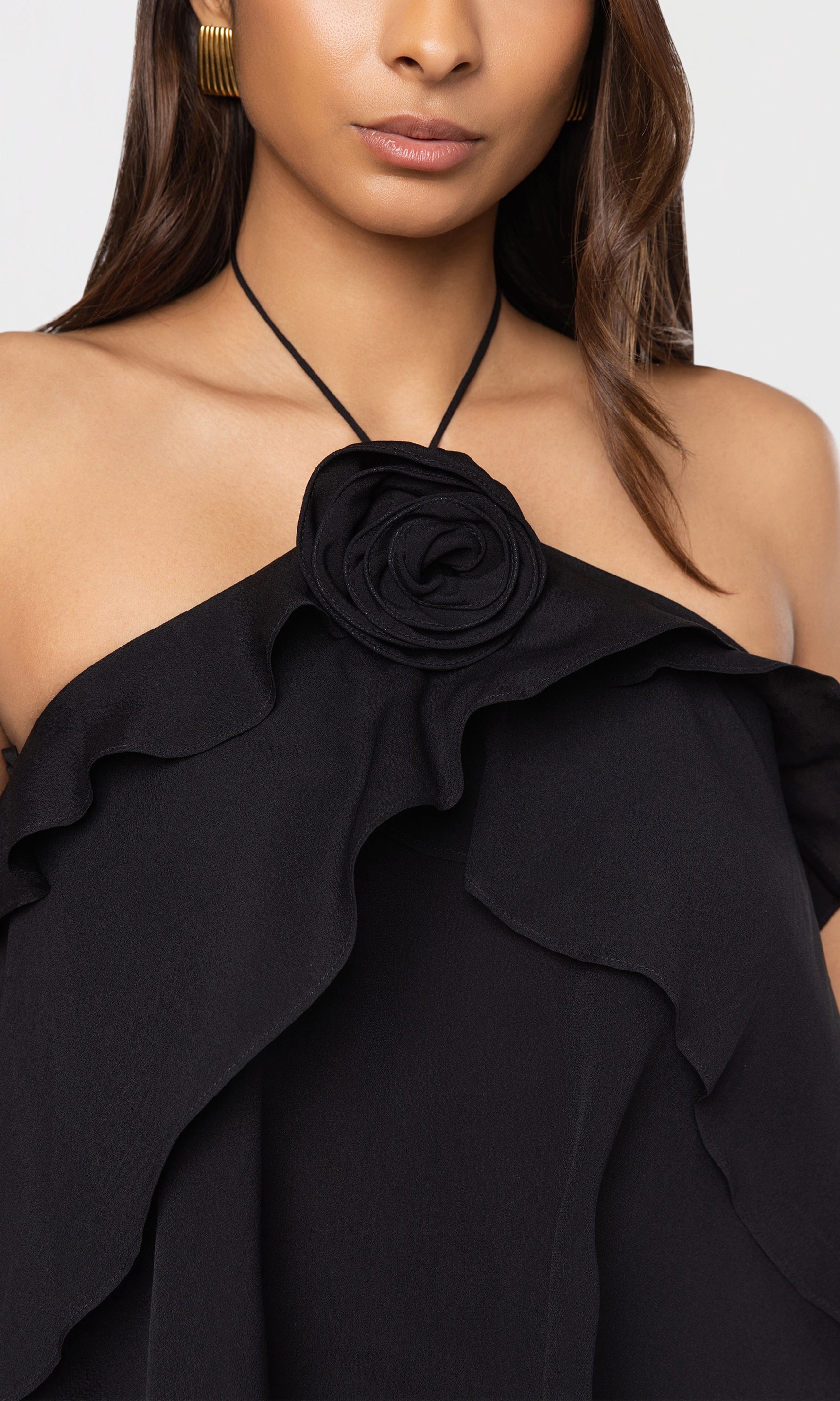 Close-up of black halter blouse with a floral design on a plain background