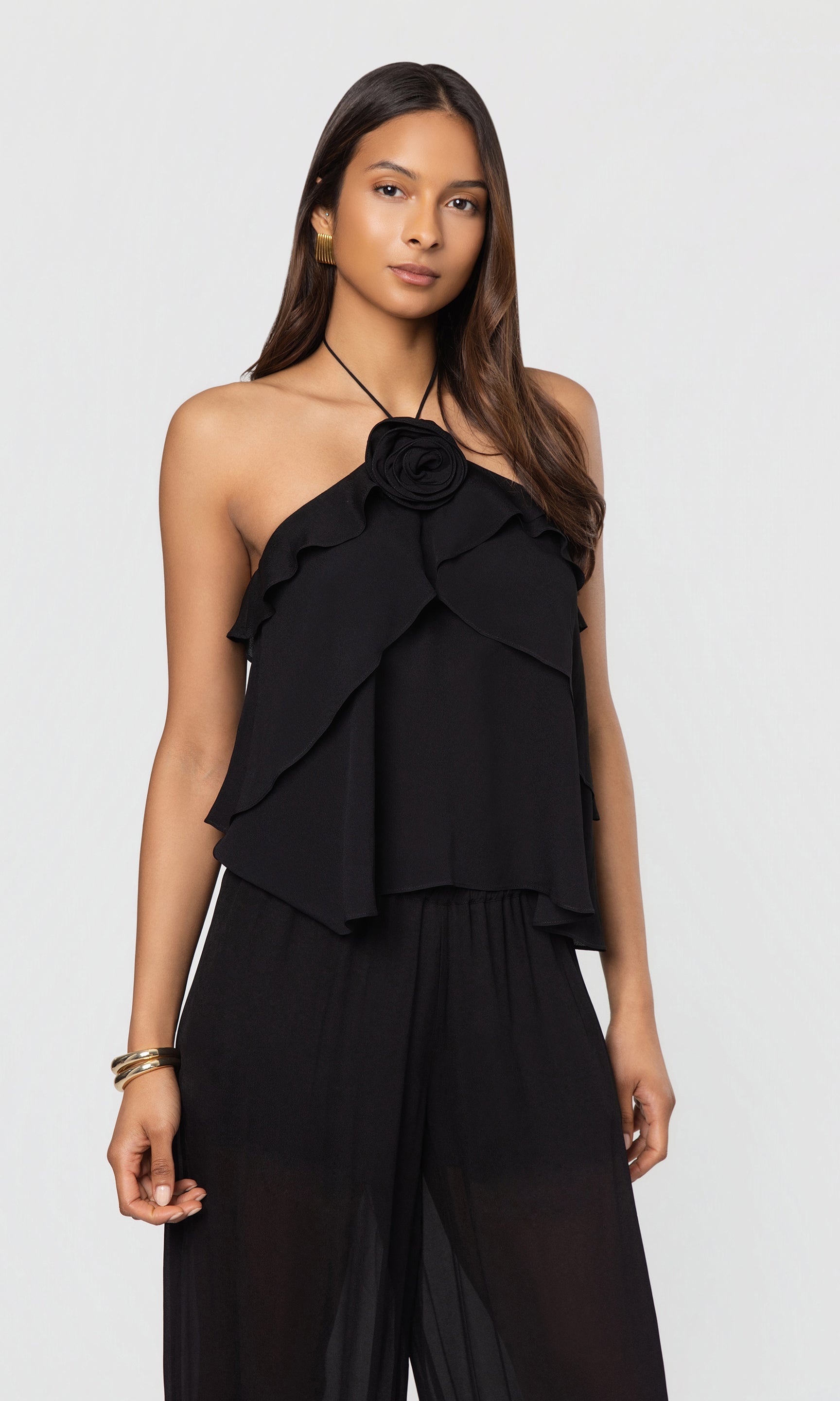 Woman wearing a black halter blouse top and wide-leg pants on a white background