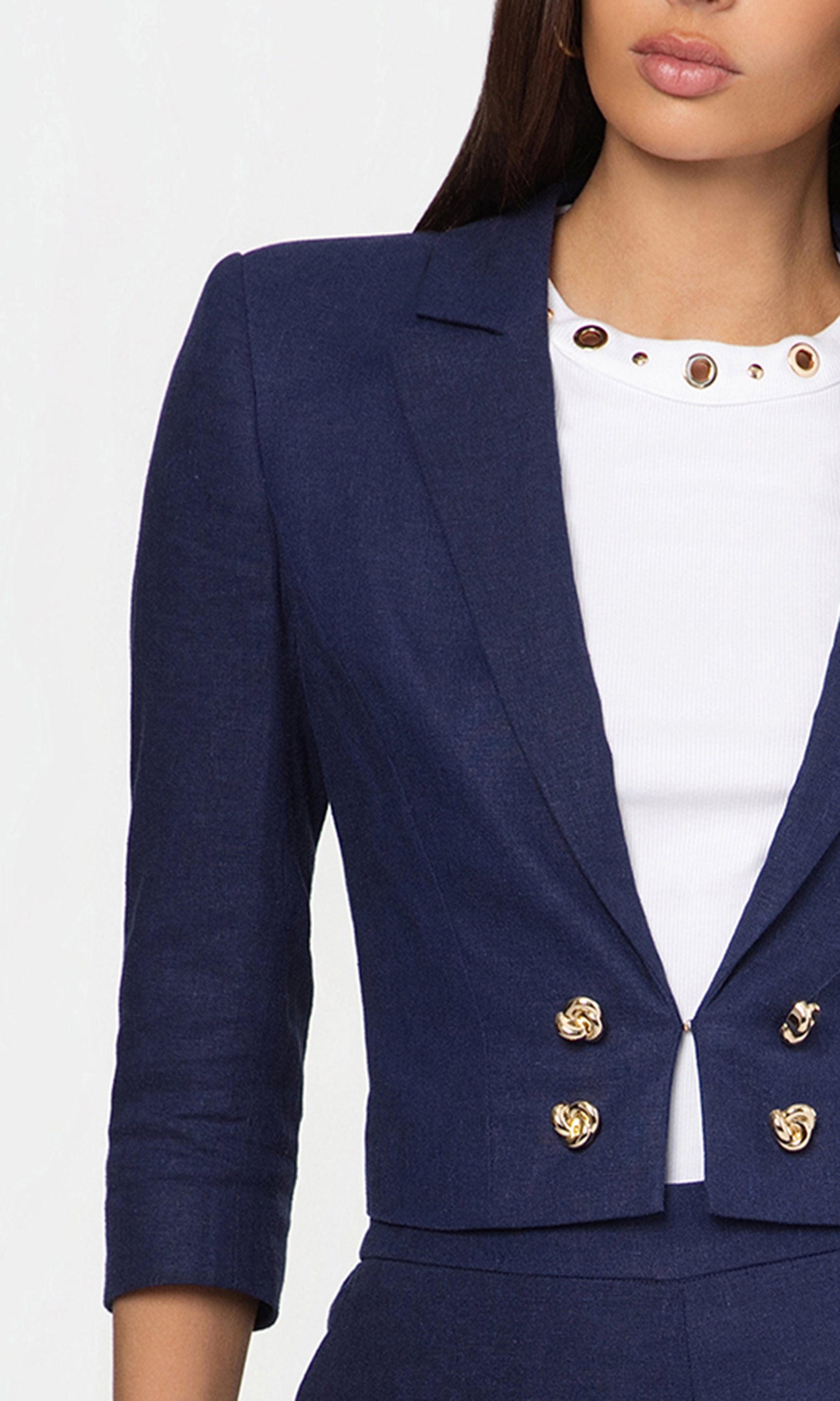 Close-up of navy blue blazer with gold buttons worn by a person on a white background