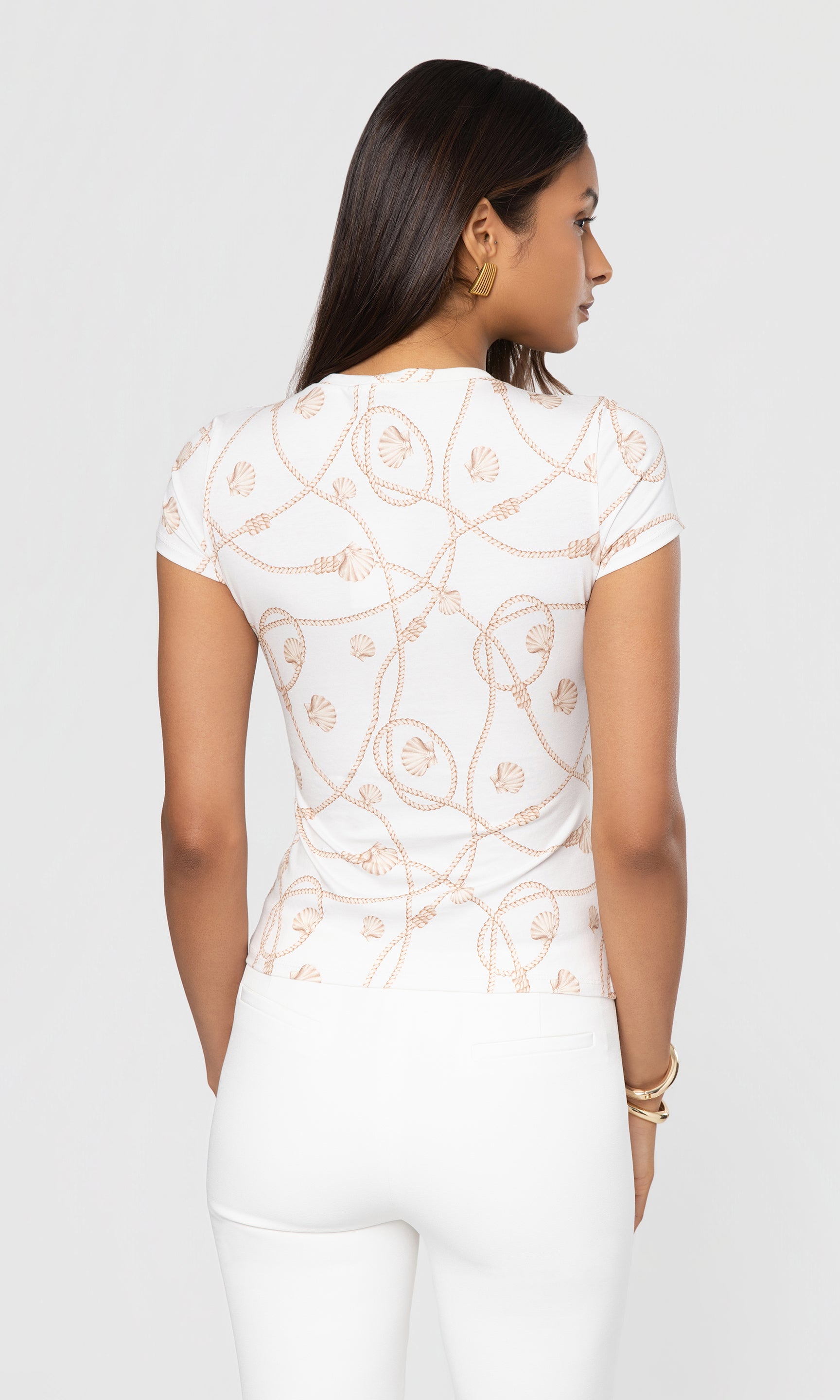 Back view of woman wearing a white top with rope print on a plain background
