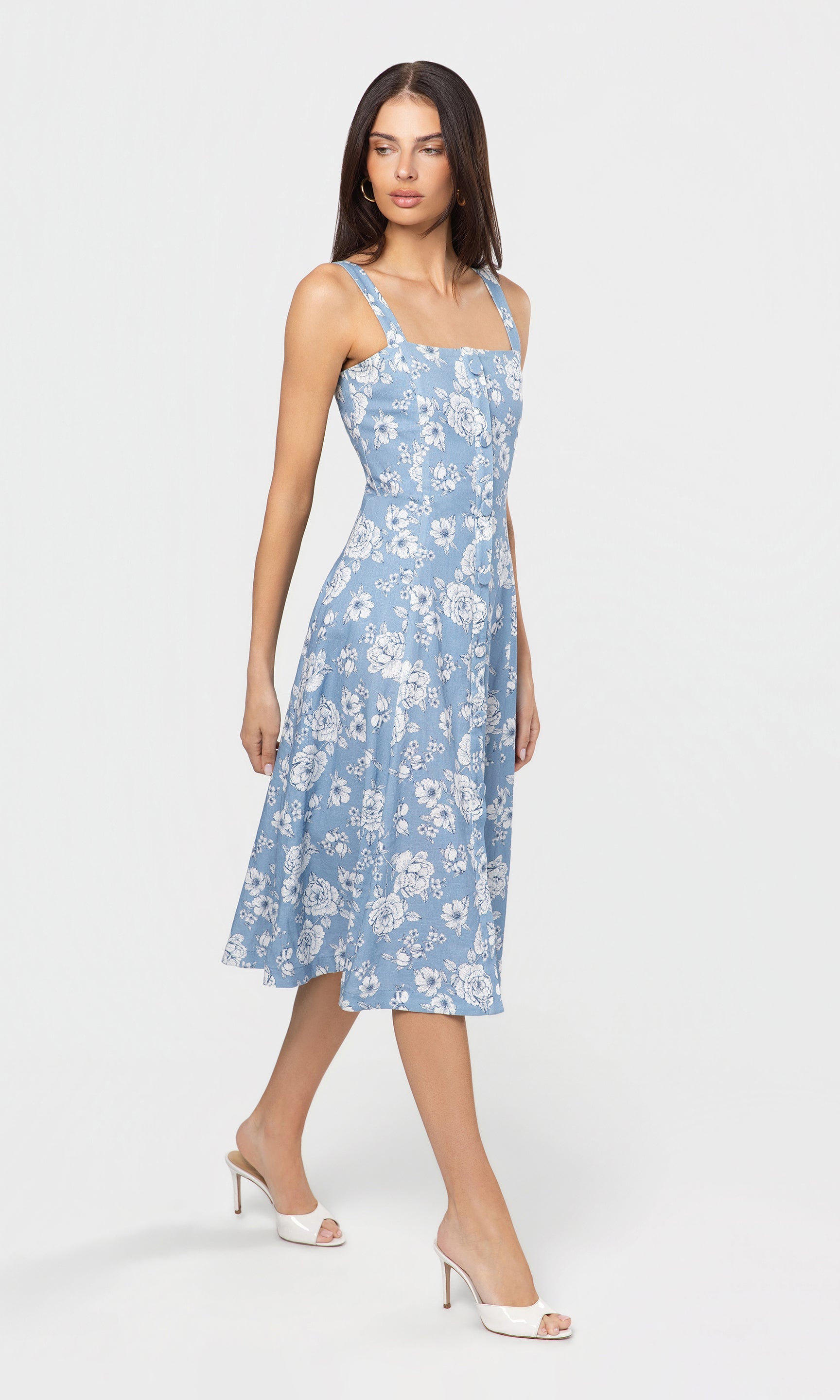 Side view of woman wearing a blue floral dress on a white background