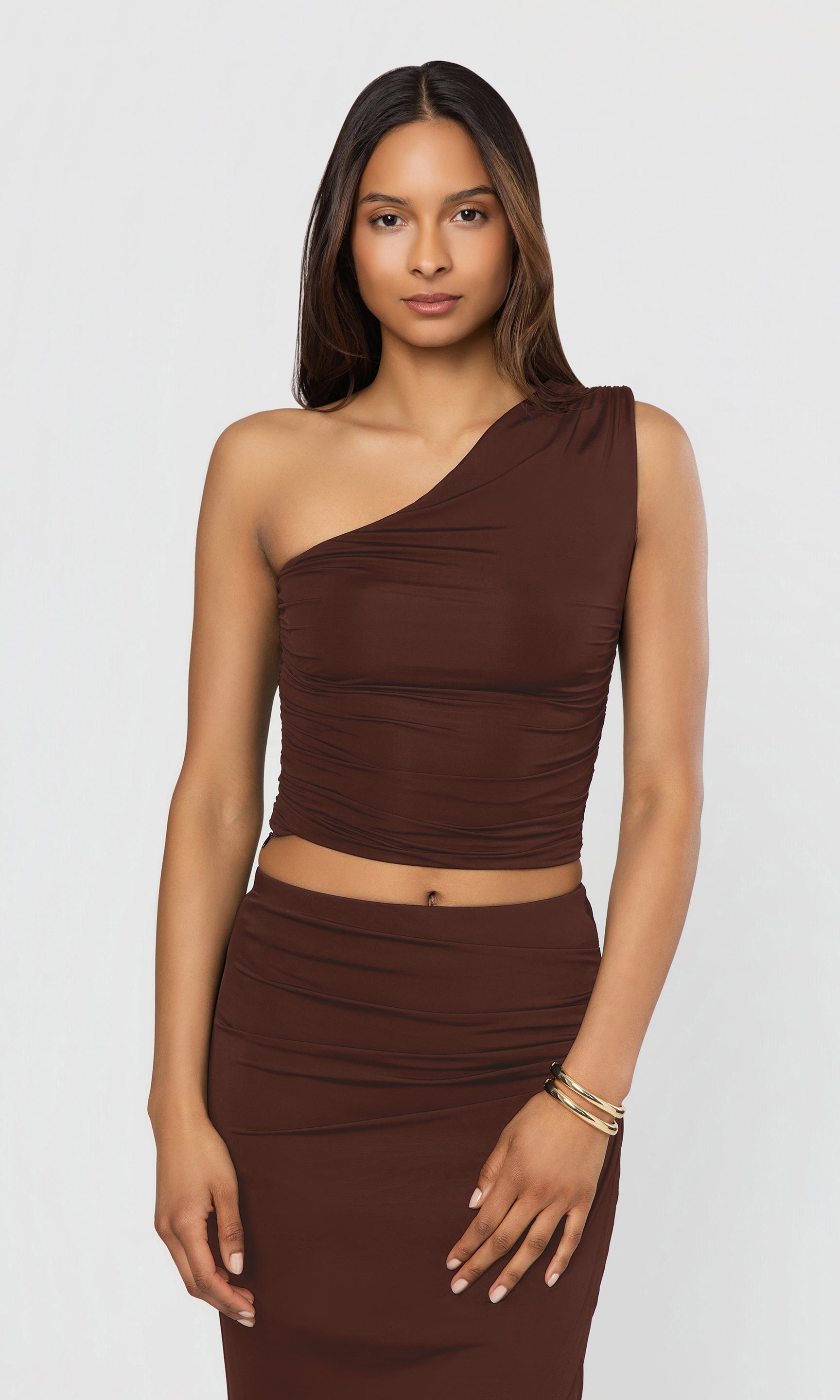 Woman wearing a brown one-shoulder top and skirt set on a white background