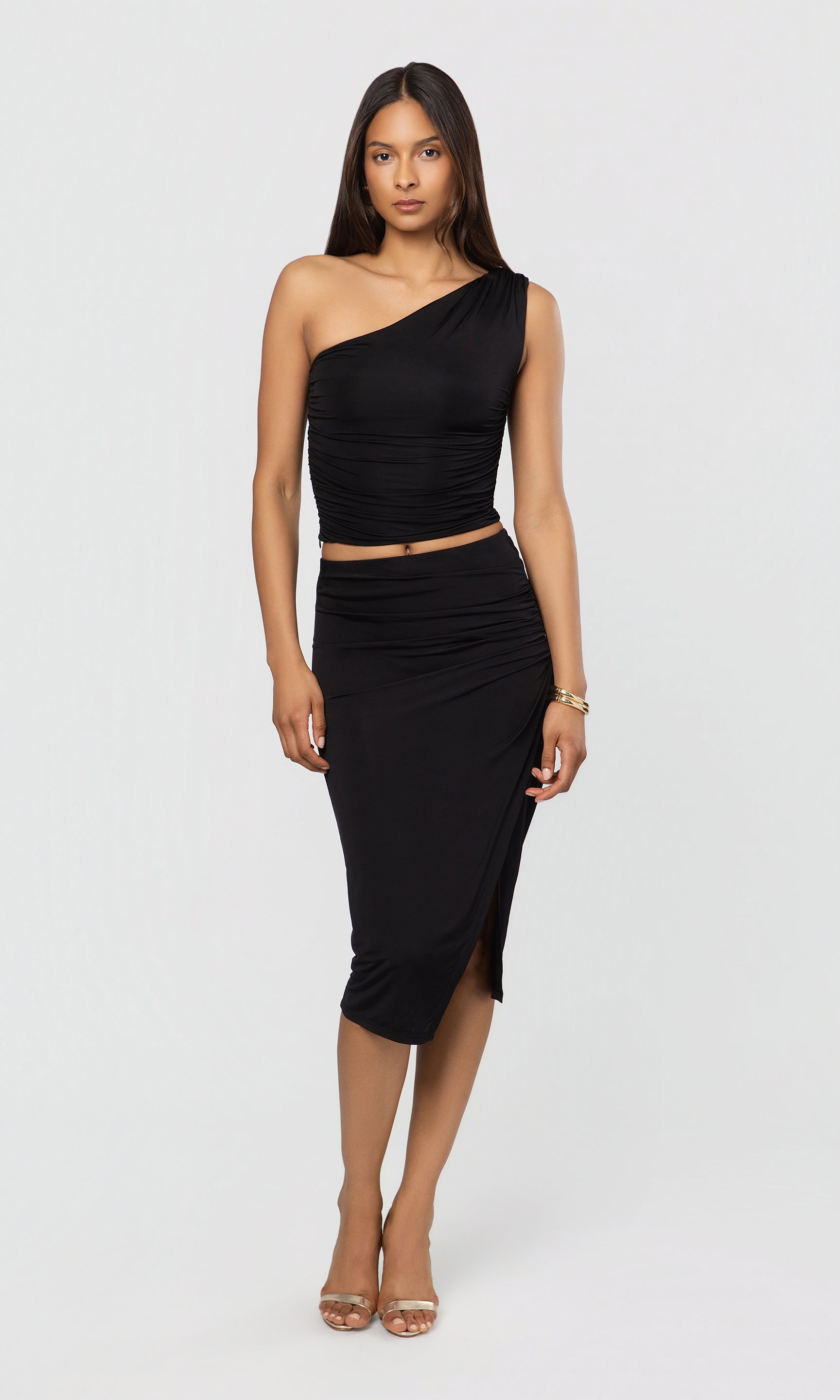 Woman wearing a black one-shoulder top and skirt on a white background