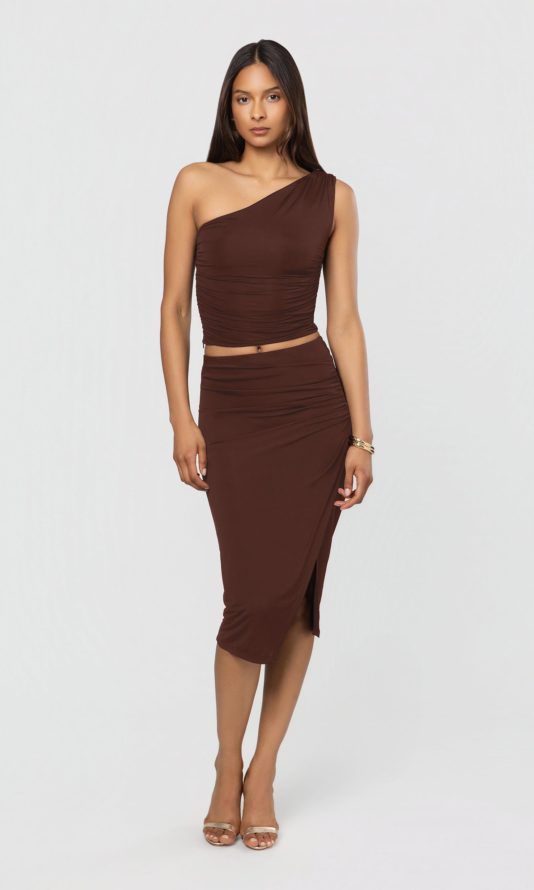 Woman wearing a brown one-shoulder top and skirt set on a white background