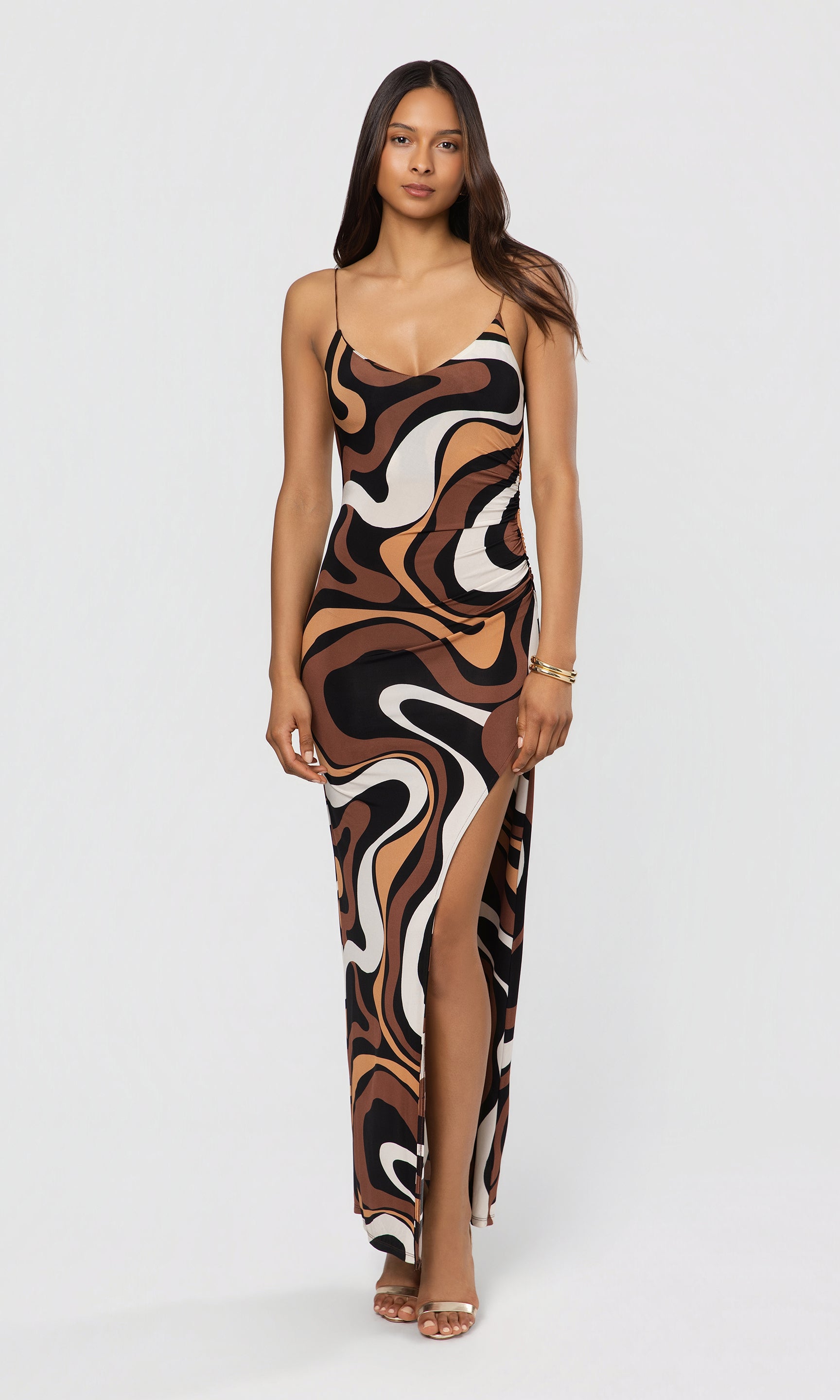 Woman wearing a patterned dress with a high slit on a white background