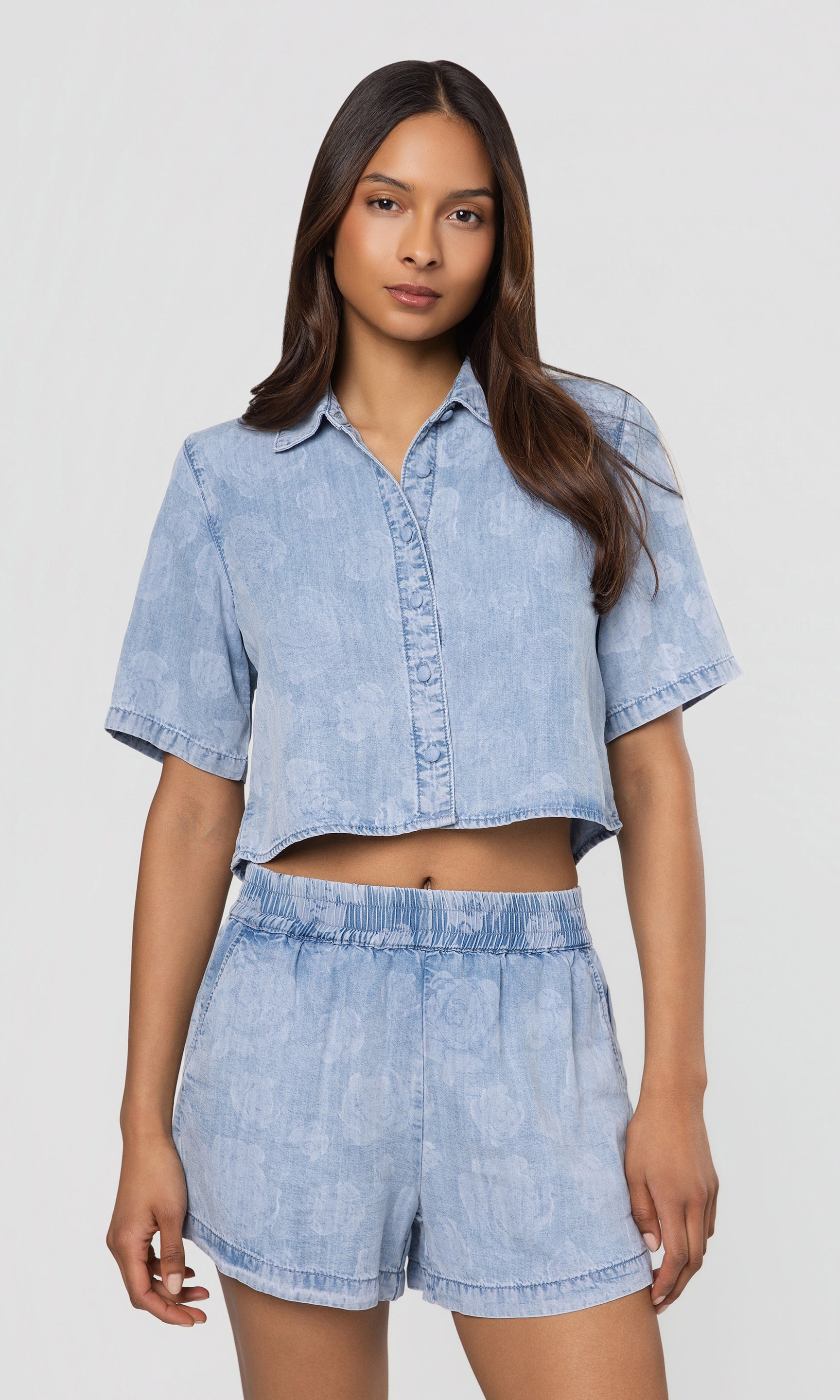 Woman wearing a light blue denim outfit on a white background