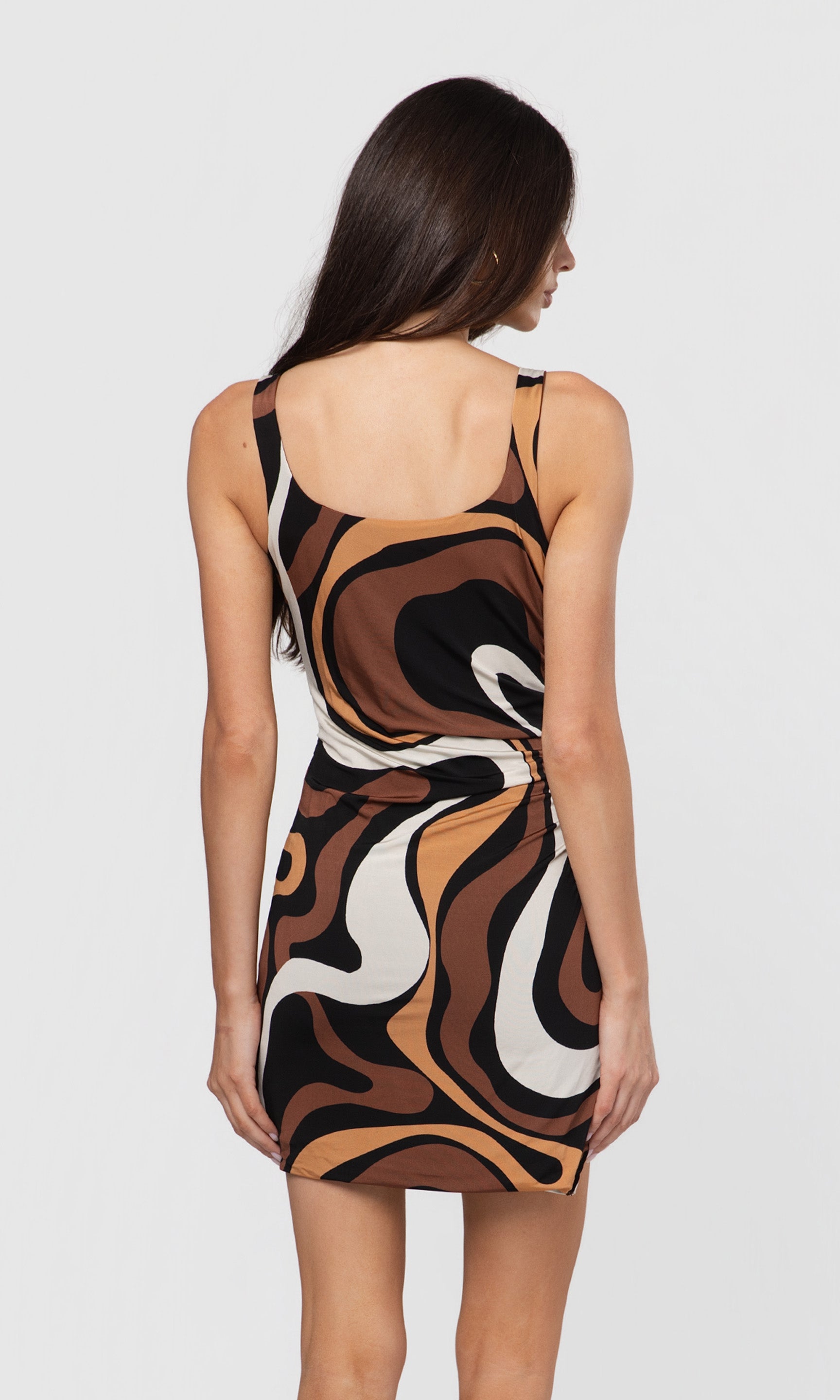 Back view of woman wearing a patterned dress on a white background
