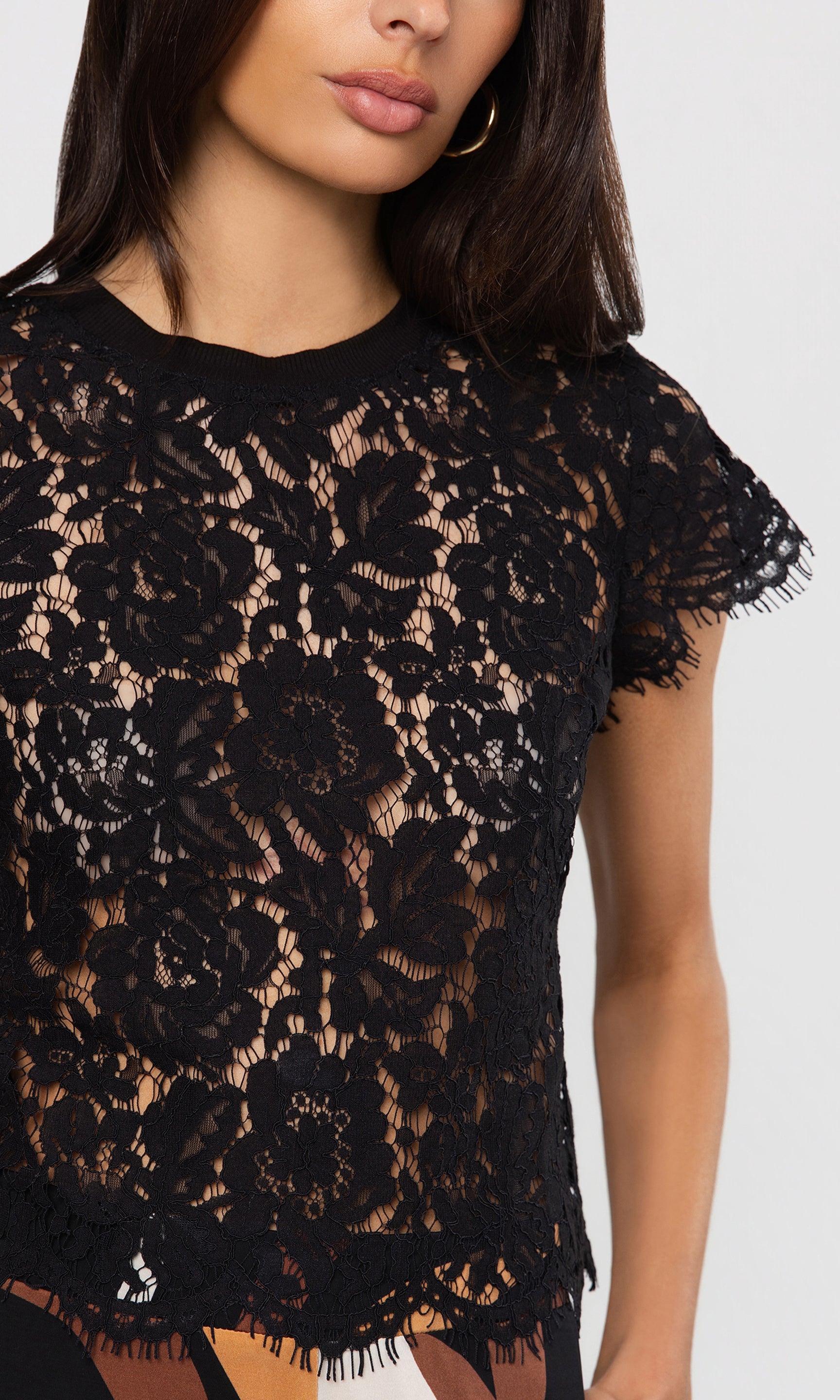 Close-up of black lace top worn by a model on a white background