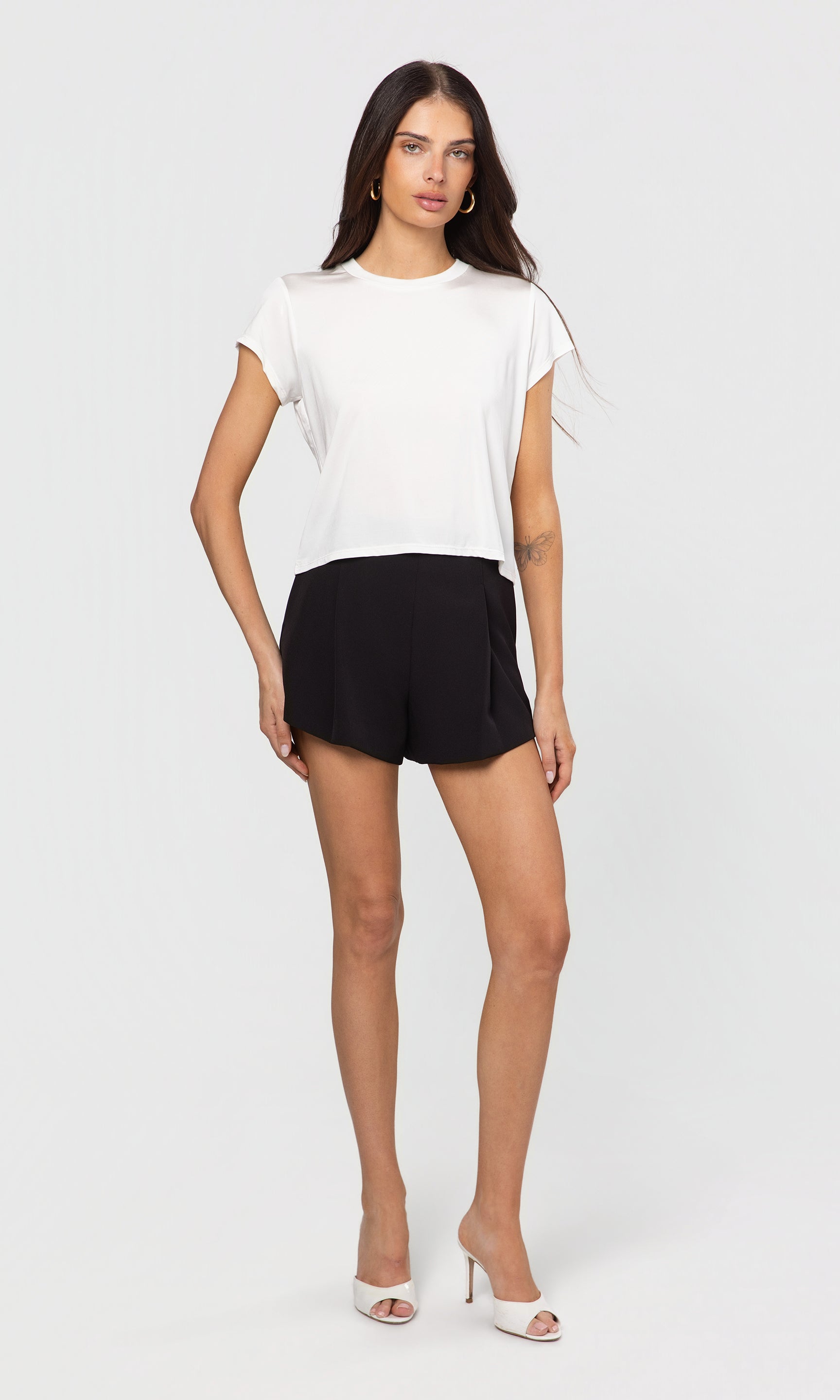Woman wearing a white top and black shorts on a white background