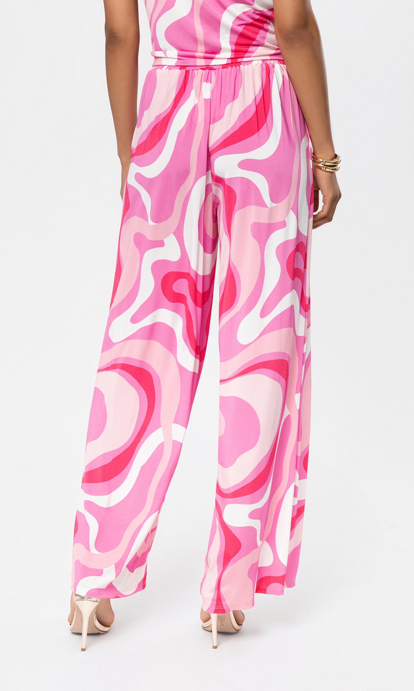 Back view of person wearing a pink and white patterned pant with matching top on a white background