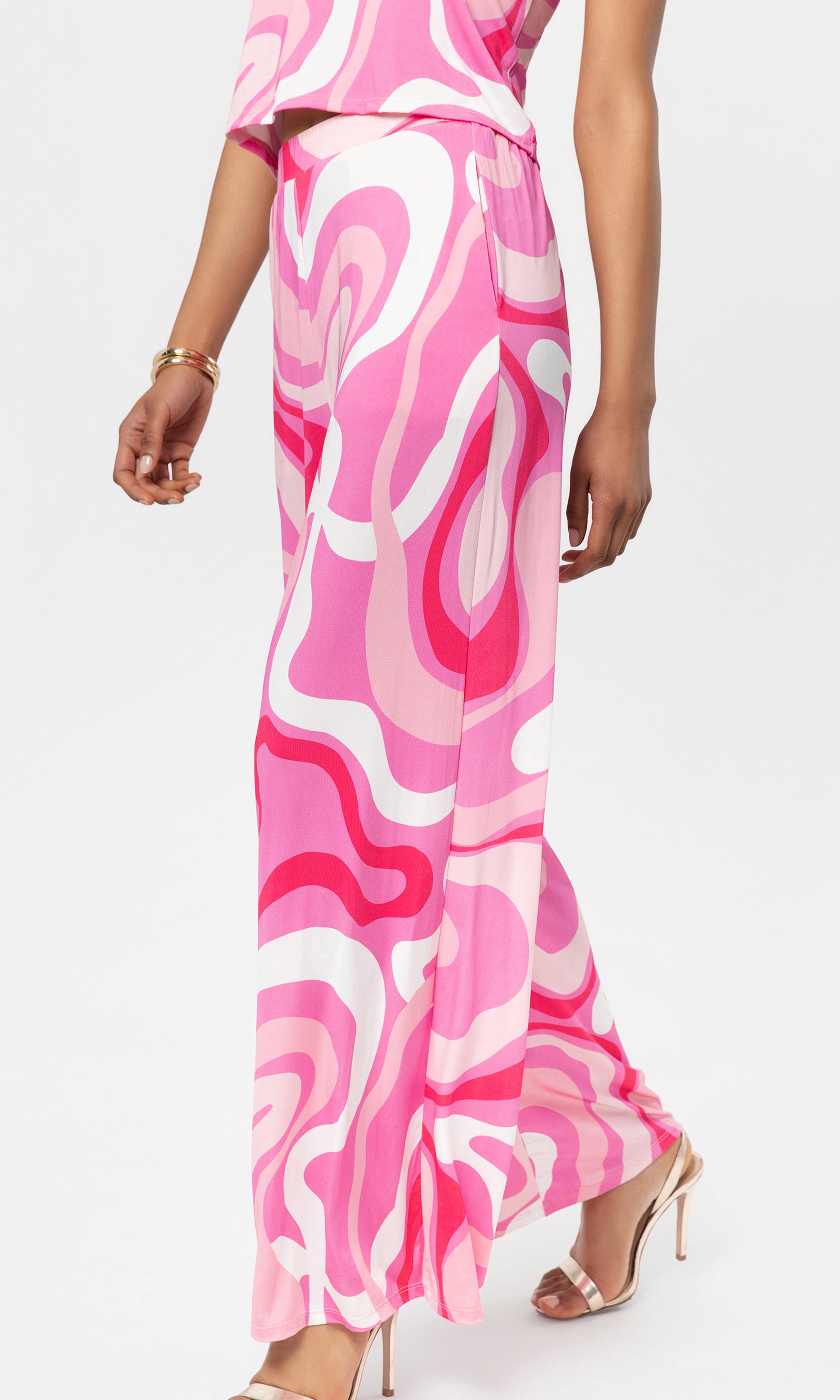 Side view of person wearing a pink and white patterned pant with matching top on a white background