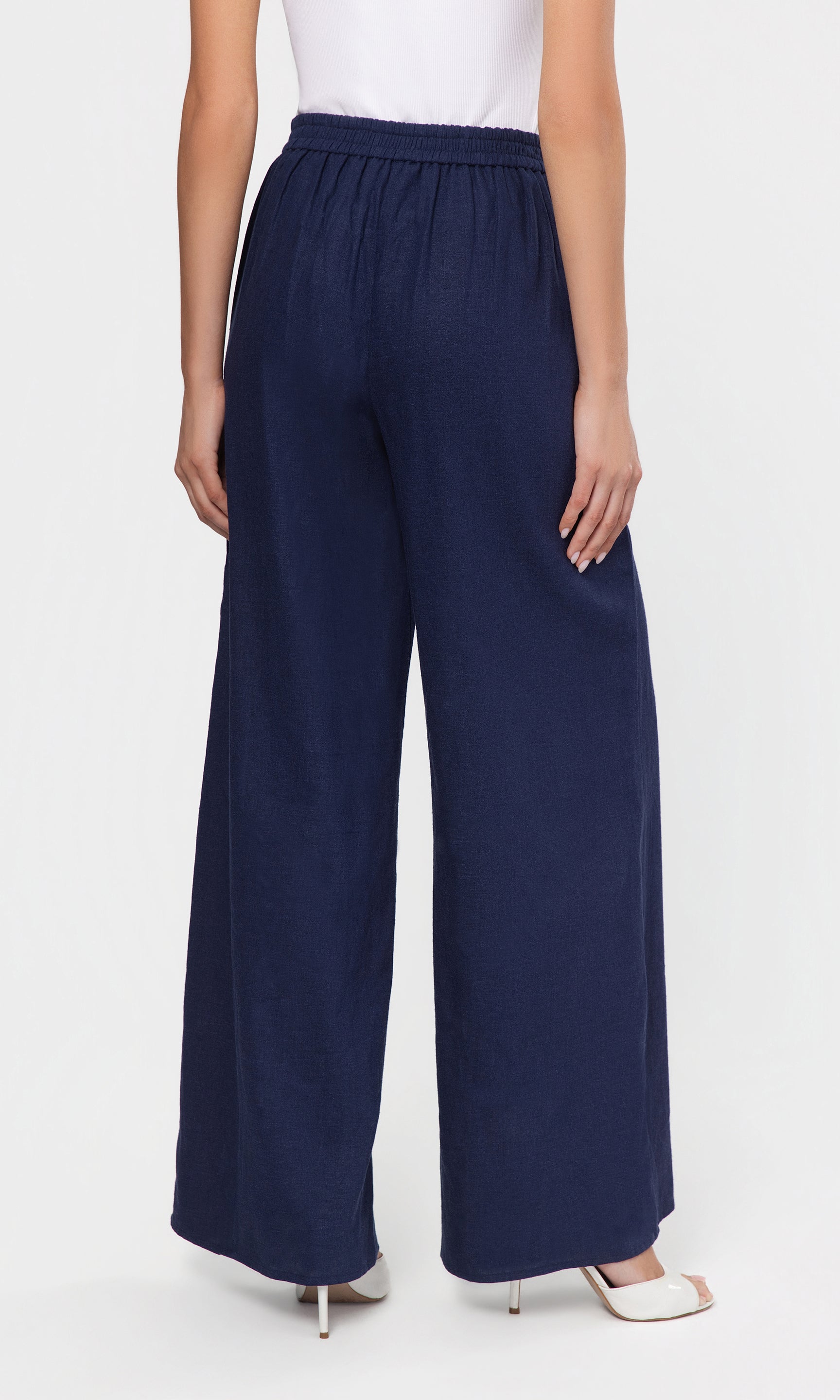 Back view of navy wide-leg pants worn by a person on a white background
