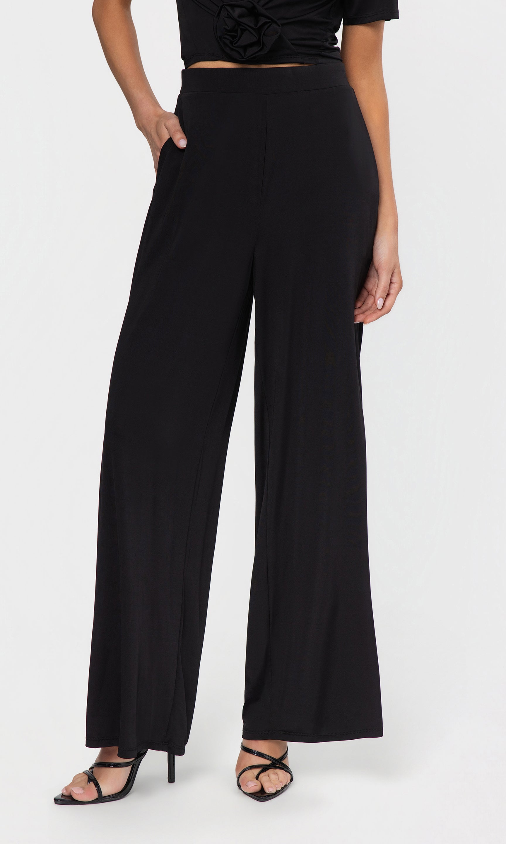 Person wearing black wide-leg pants on a white background