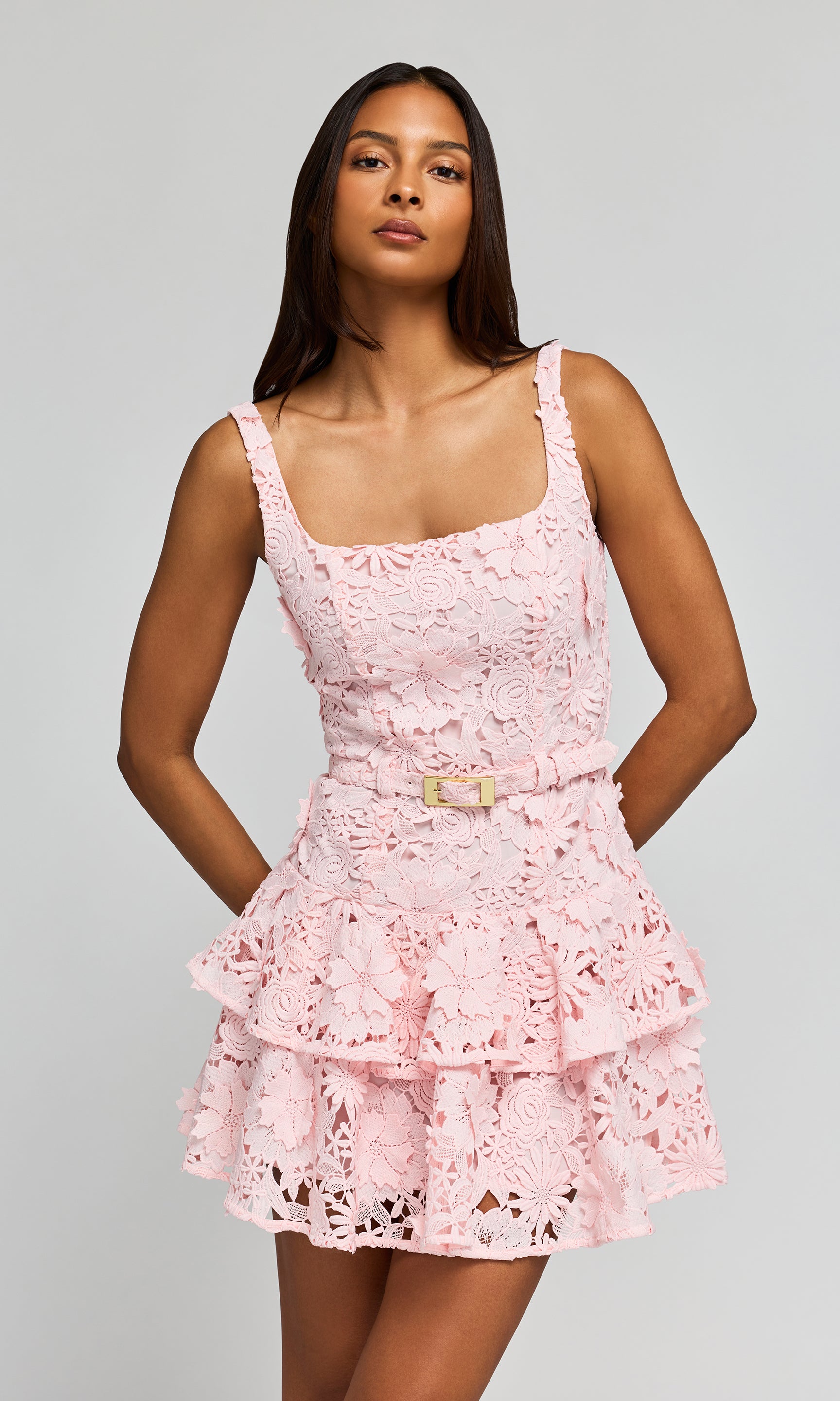 Woman wearing a pink lace dress against a gray background