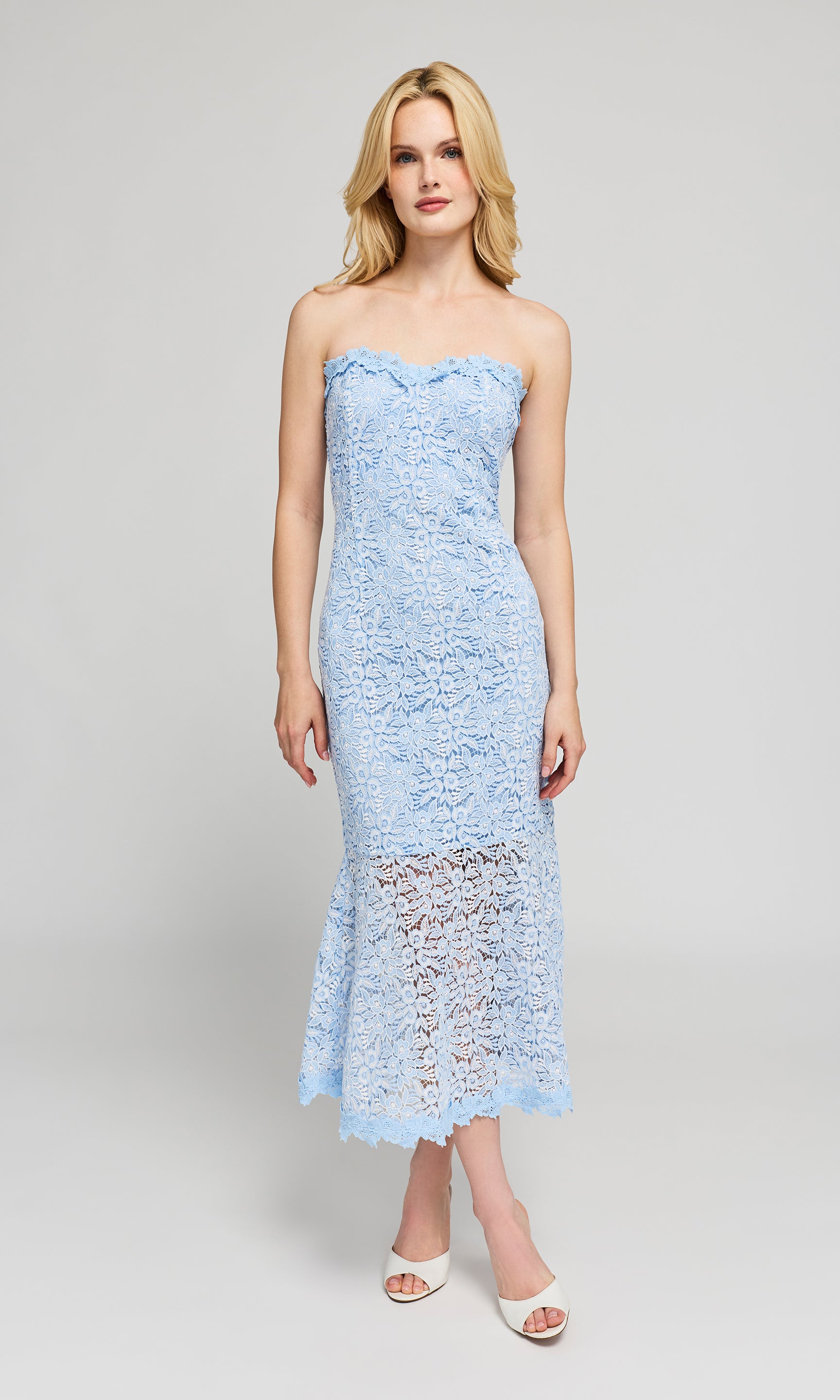 Woman wearing a light blue strapless lace dress on a white background