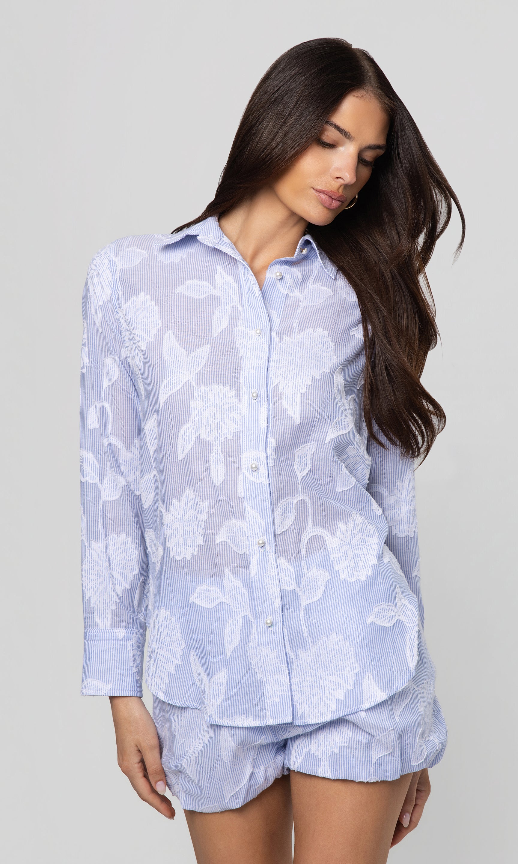 Woman wearing a light blue top and shorts set with a floral pattern on a plain background